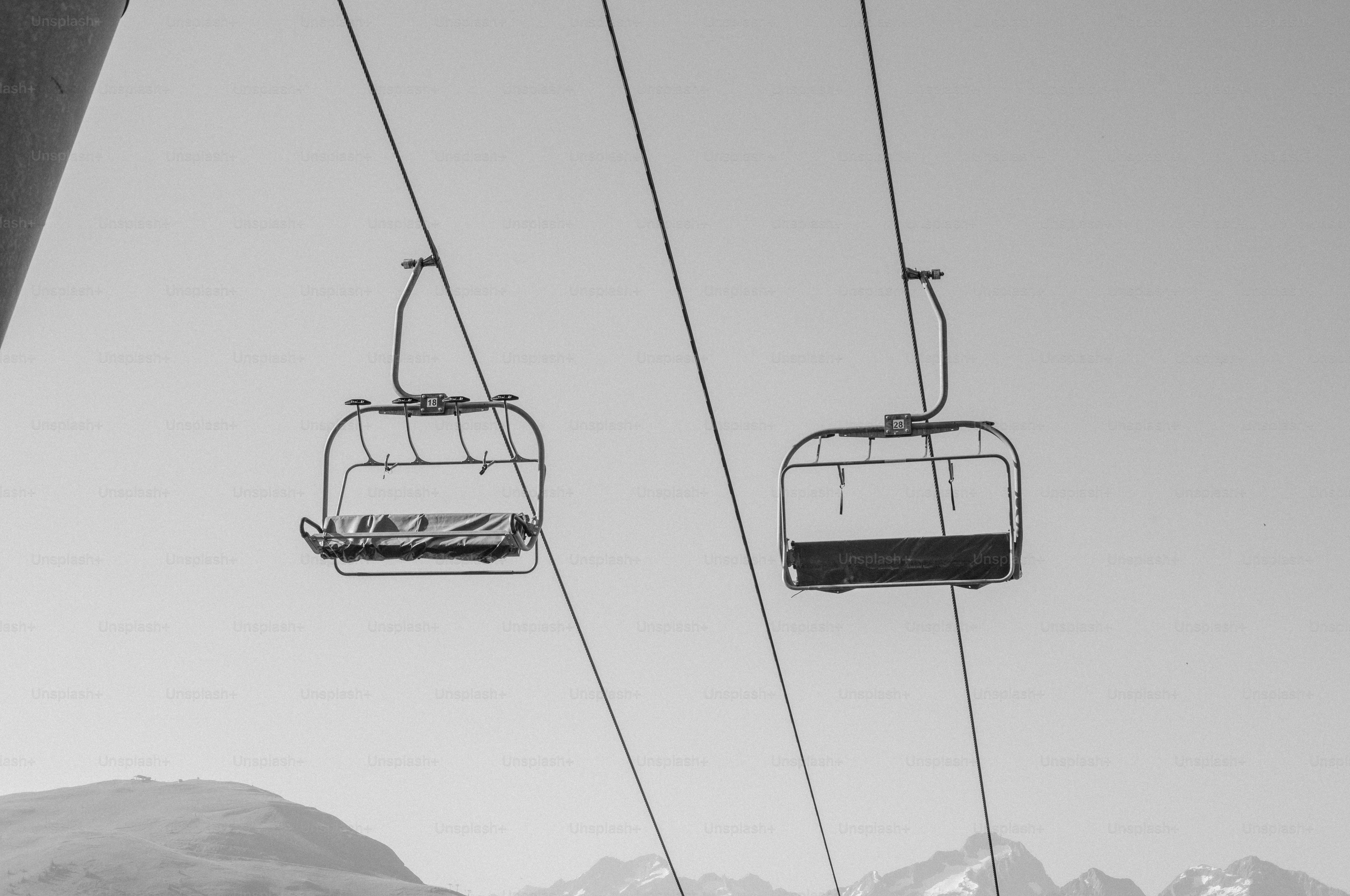 Two empty ski lift chairs against bright sky