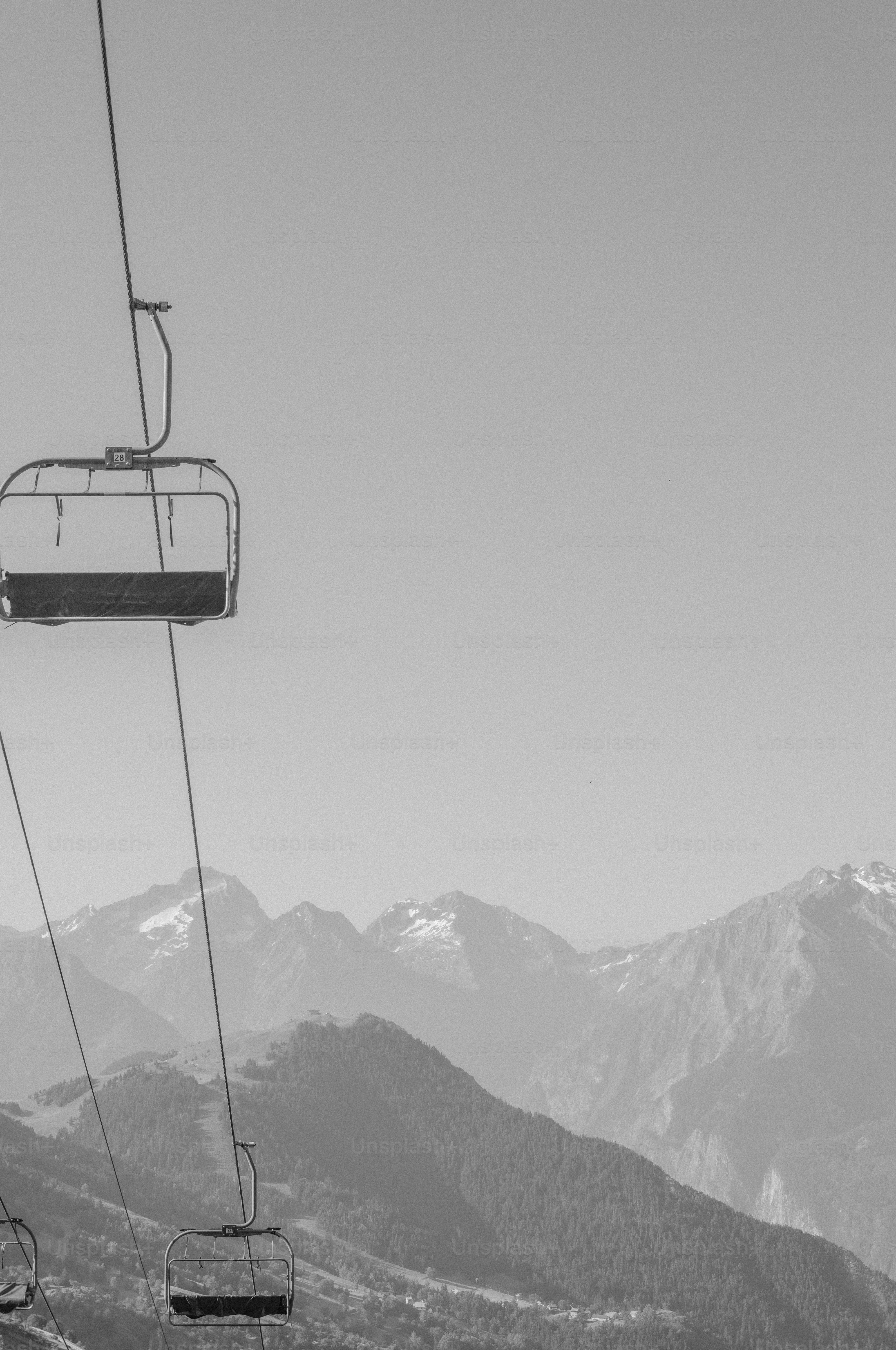 Cadeiras de teleférico monocromático e cadeia de montanhas