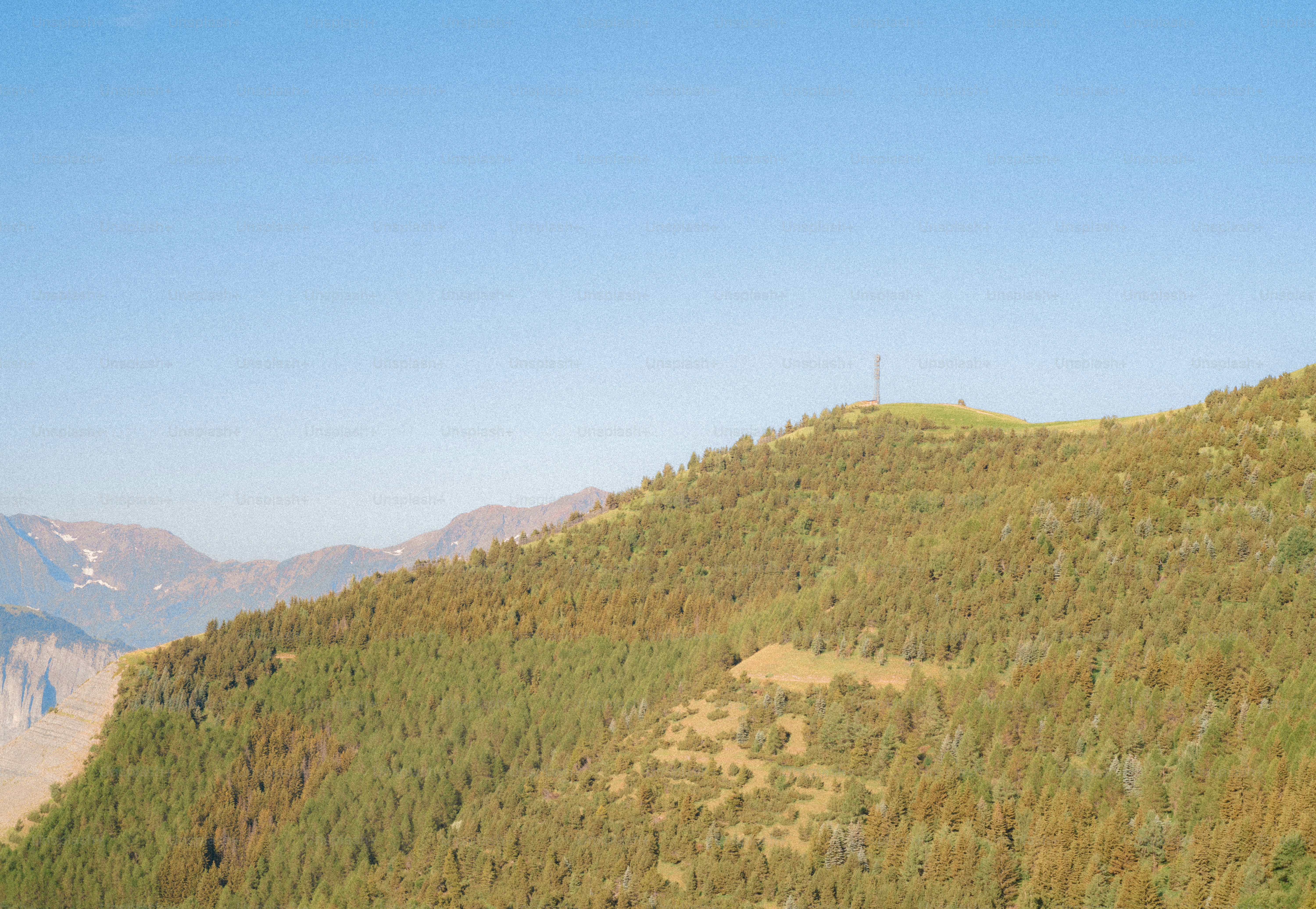 Green mountain with tower under clear blue sky