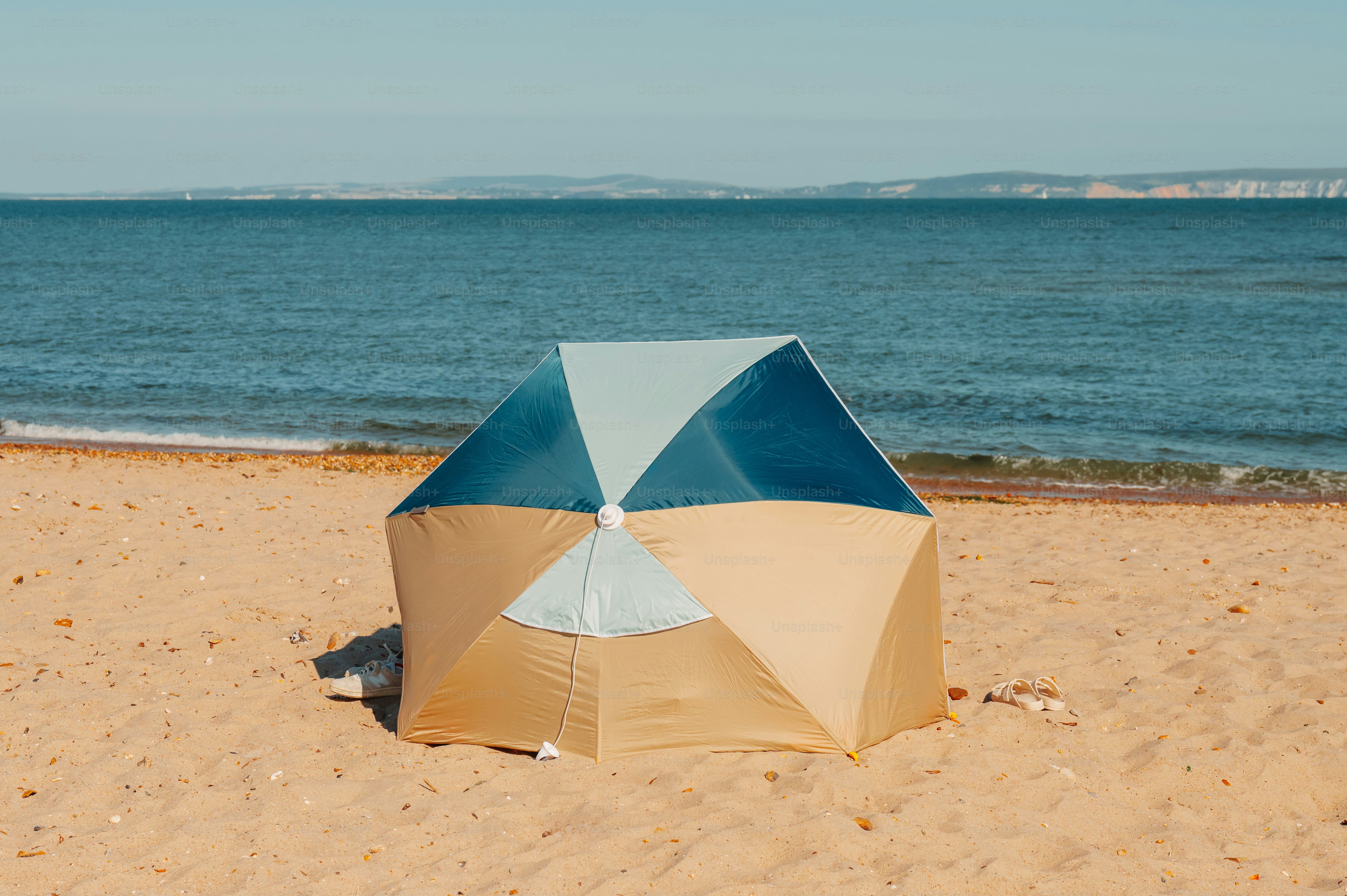 Beach tent pitched on sandy shore by sea