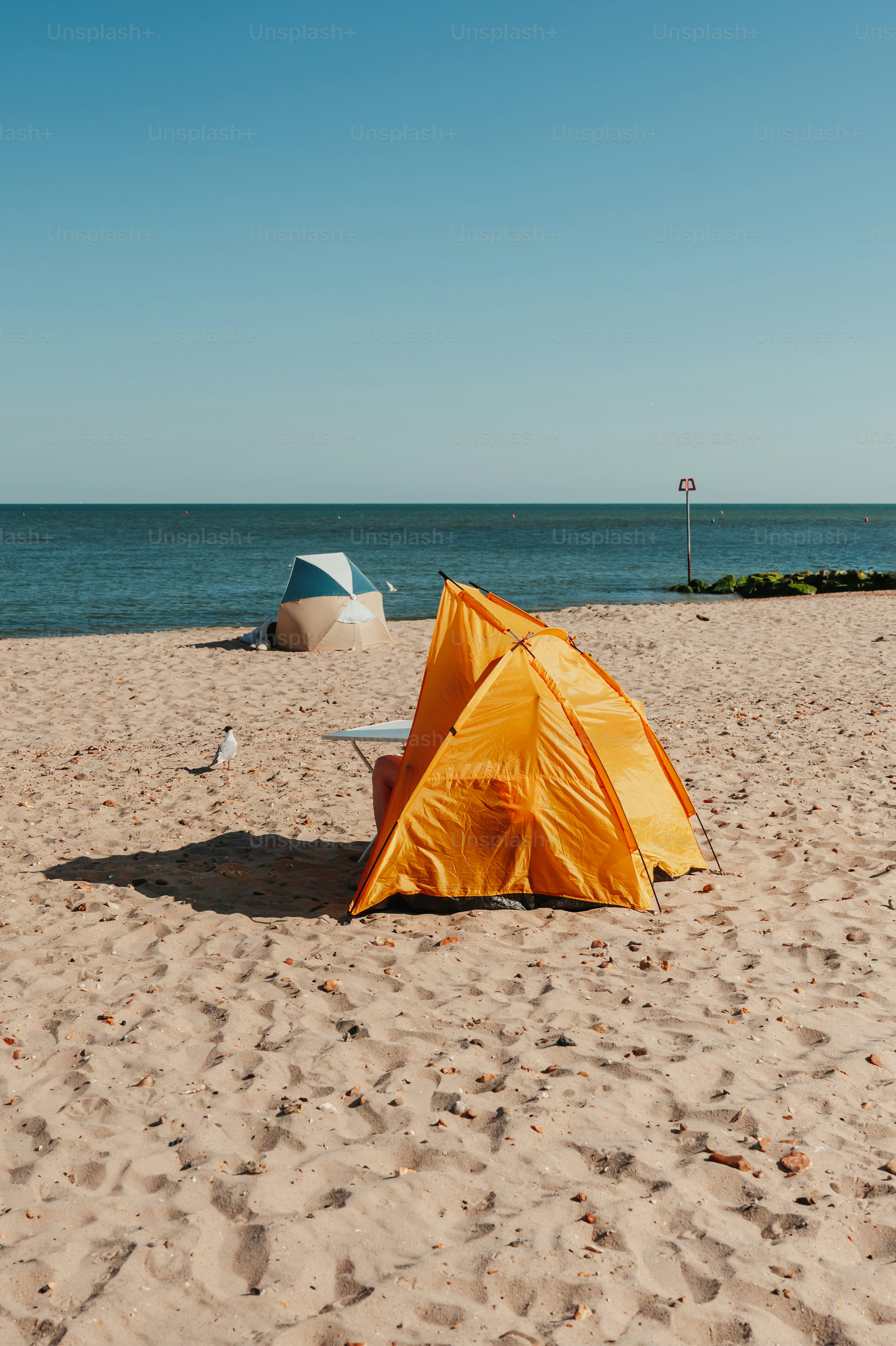 Orange and blue beach tents on sandy shore