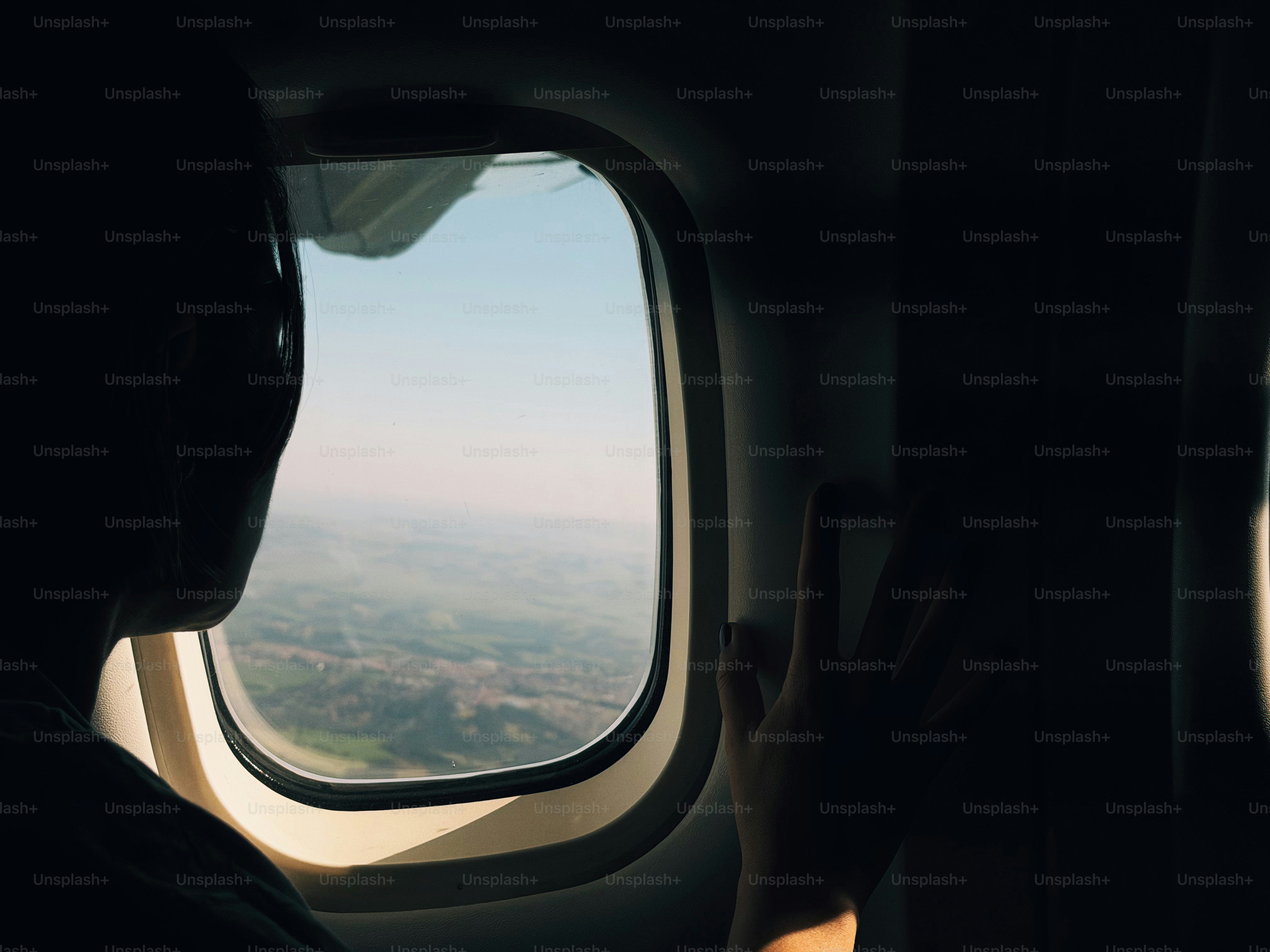 Person looking out airplane window during flight