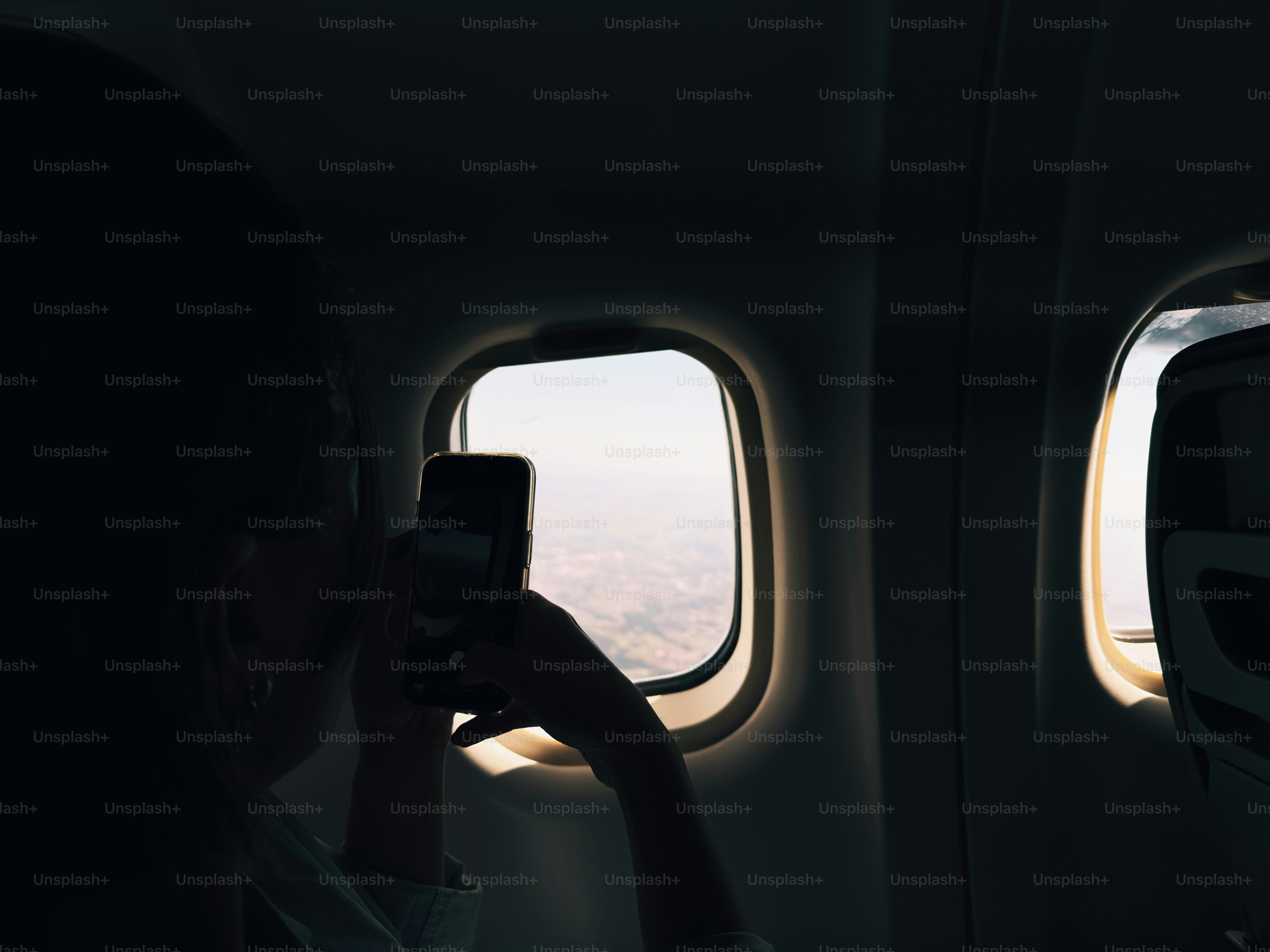 Silhouette taking picture through airplane window