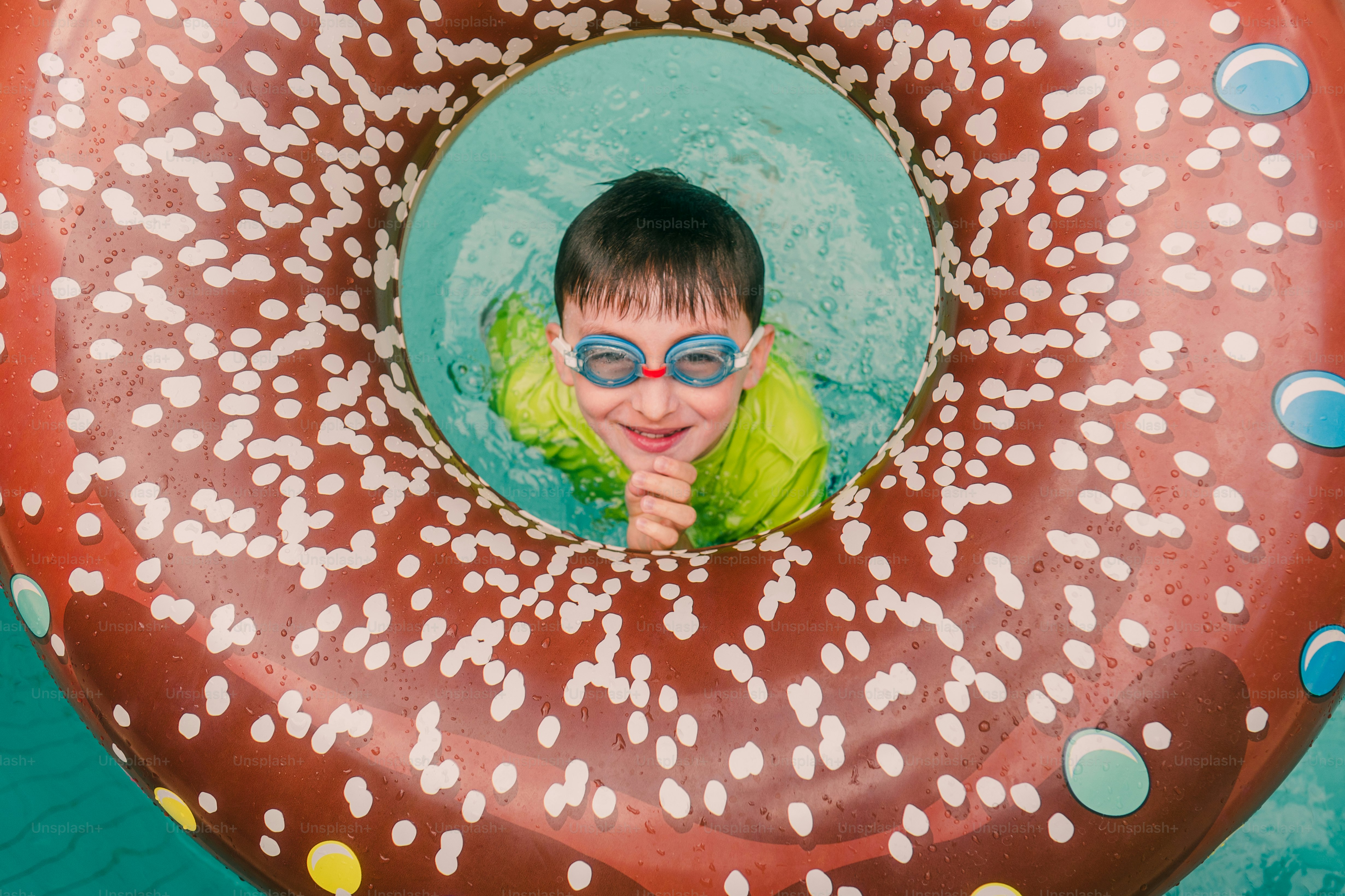 Lächelnder Junge mit Schutzbrille im Donut-Schwimmbecken