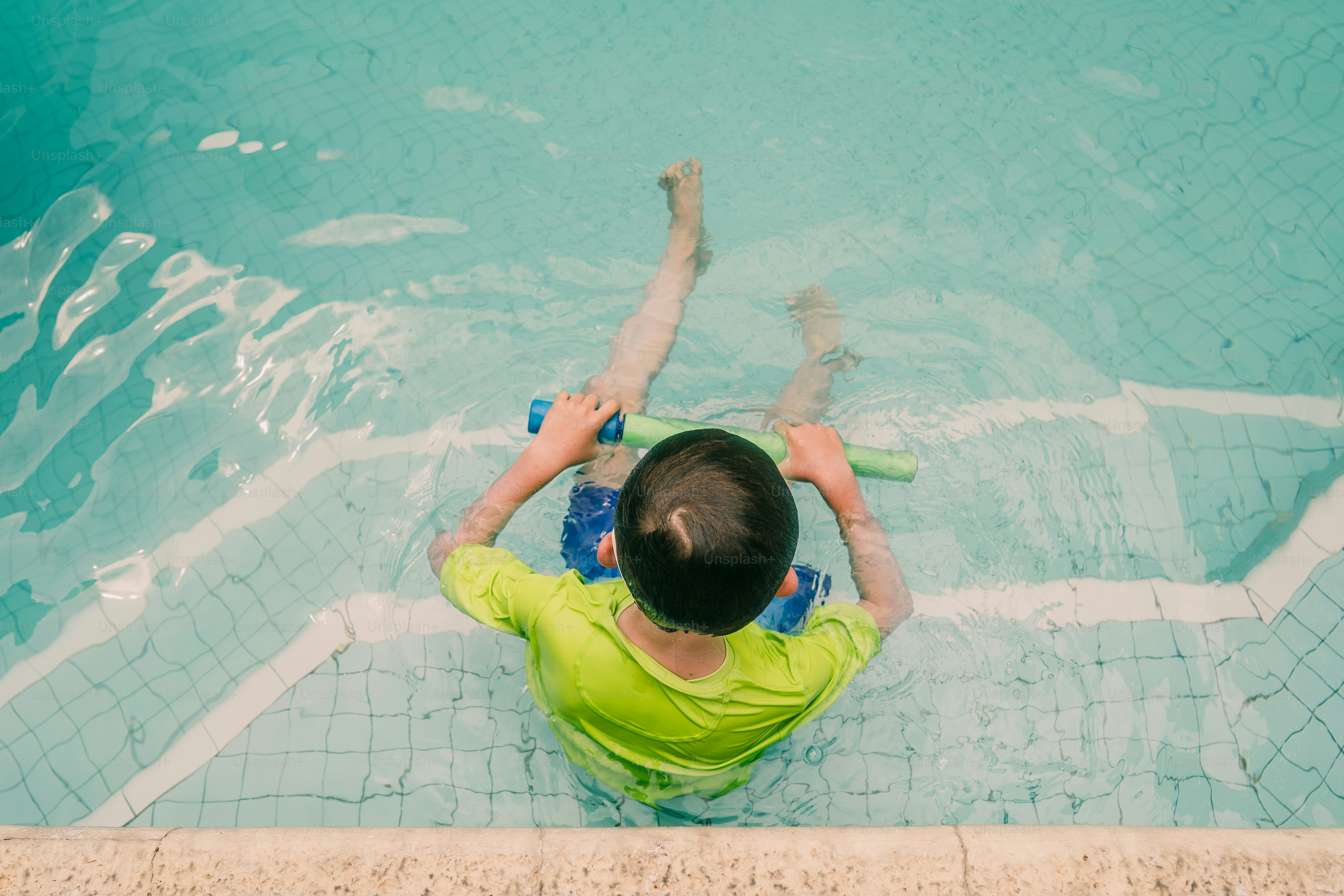 Junge im grünen Hemd sitzt auf den Poolstufen