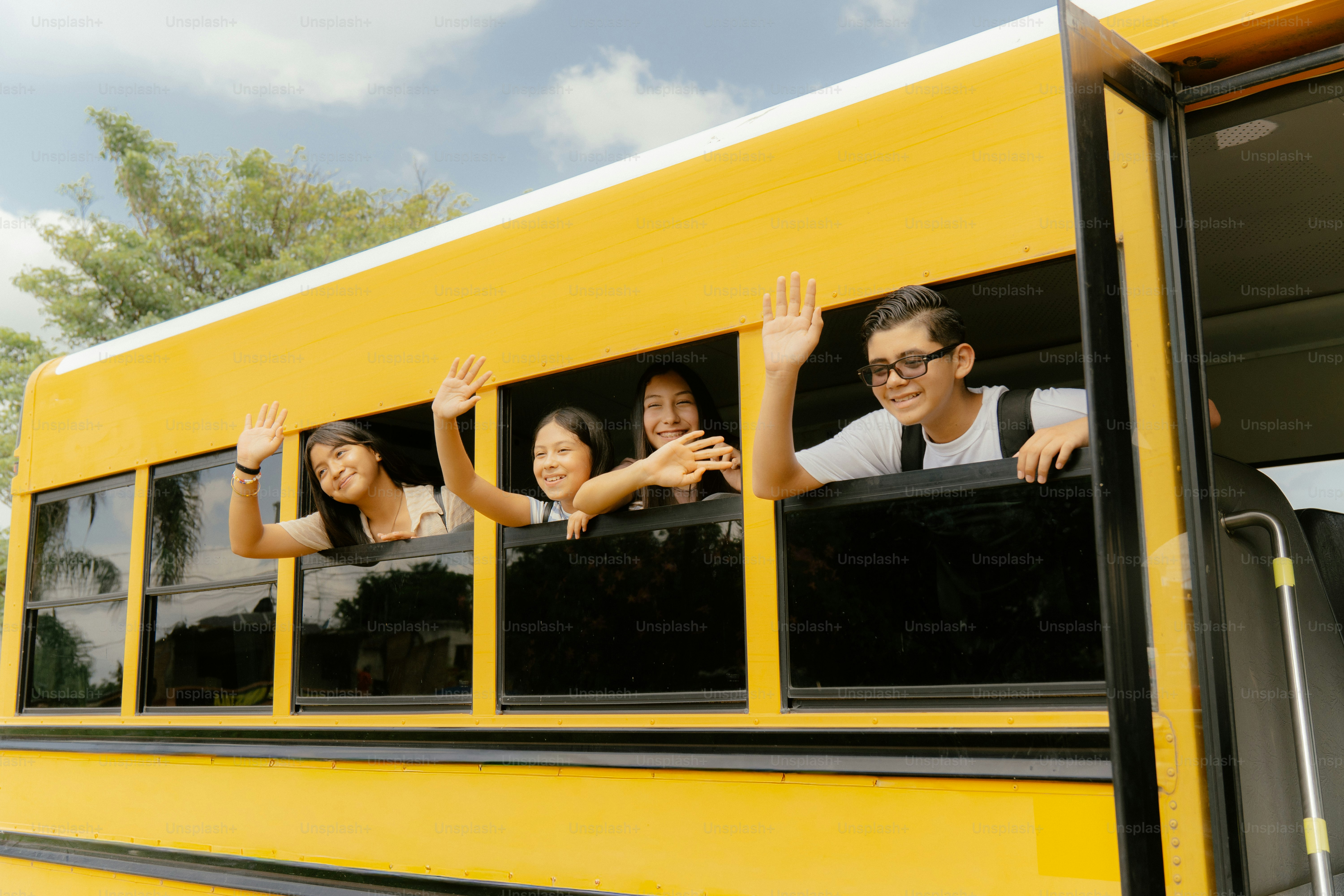 Alunos acenando nas janelas amarelas dos ônibus escolares