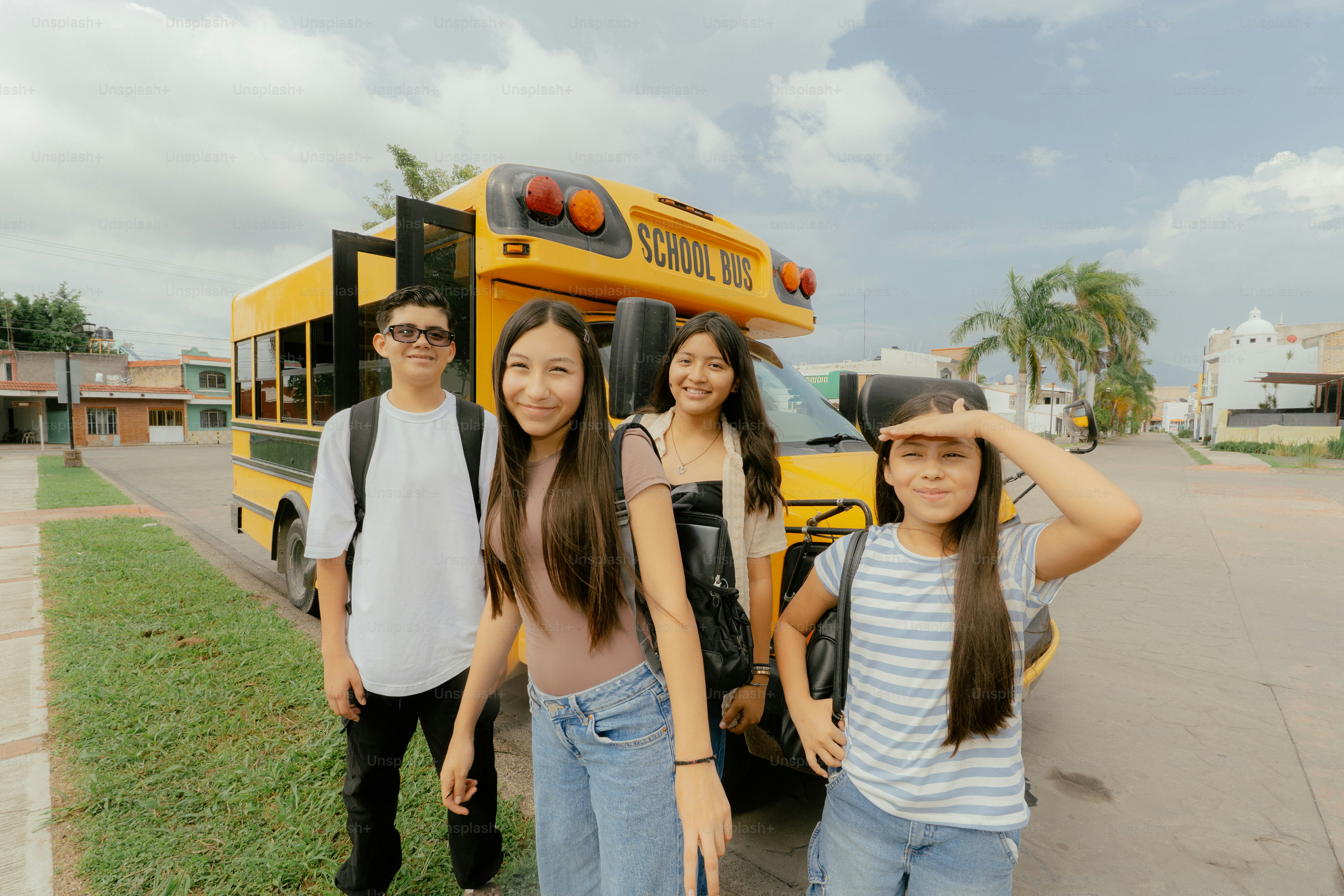 Students standing in front of a yellow school bus