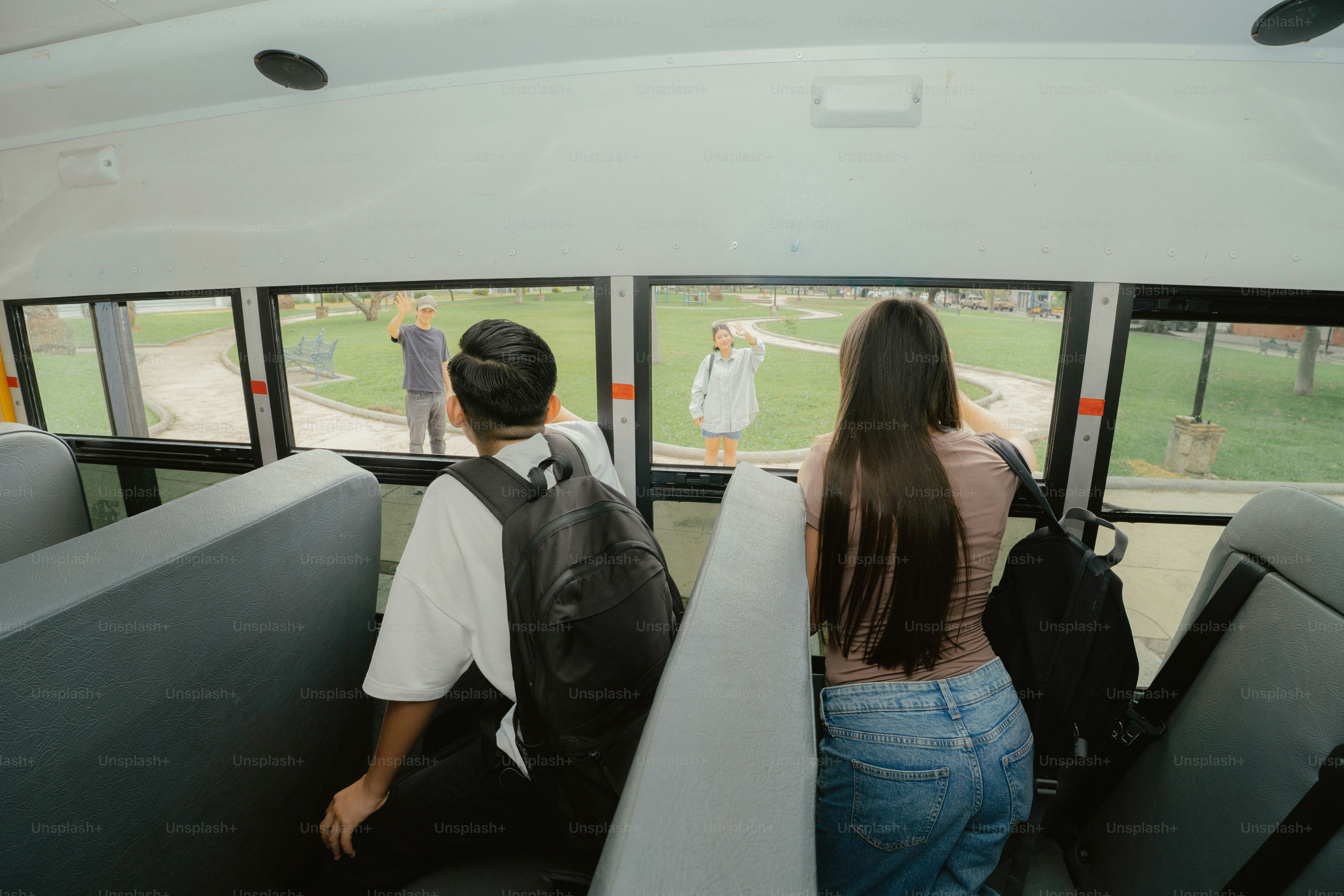 Students on school bus looking at people waving