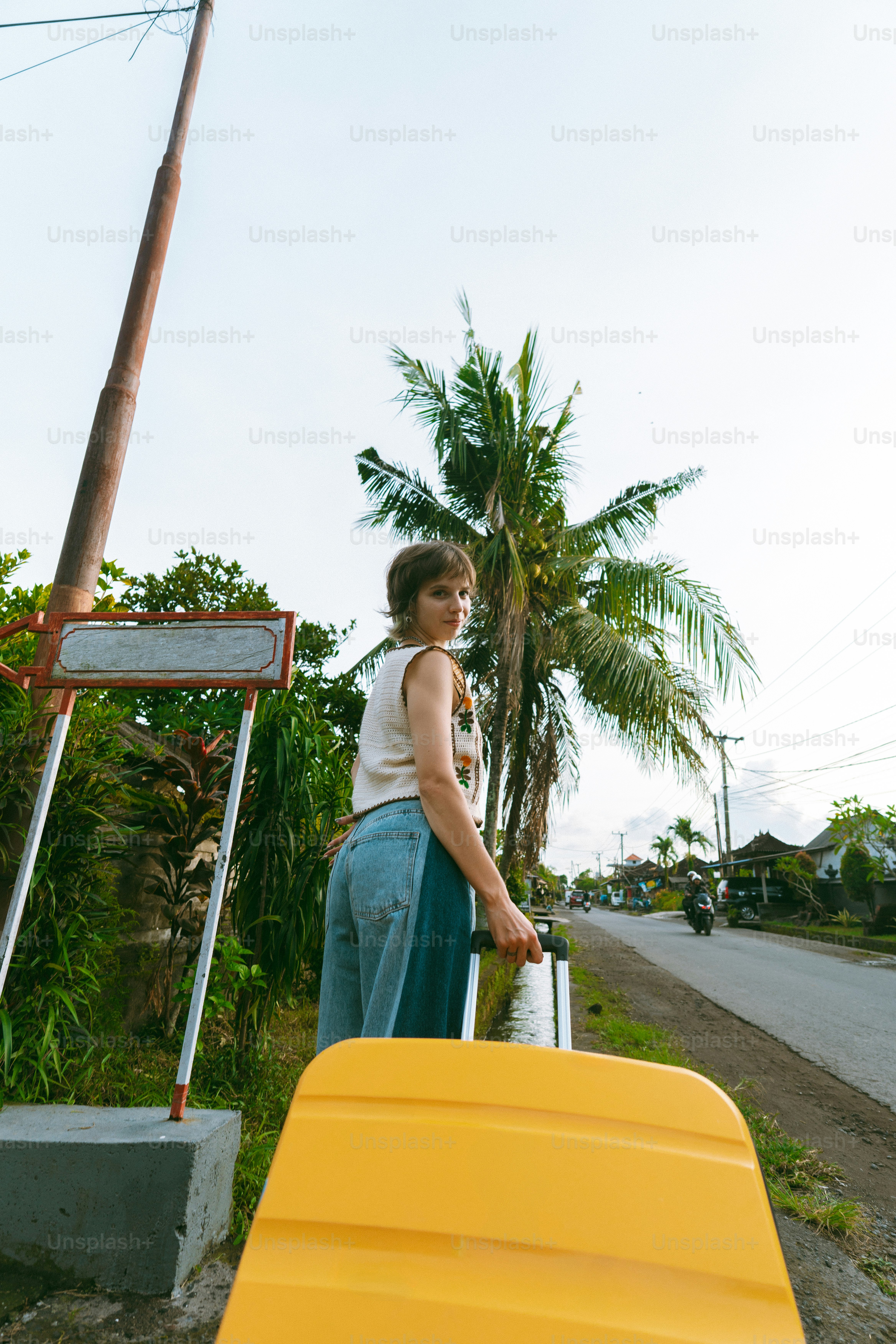 Woman with yellow suitcase on tropical vacation