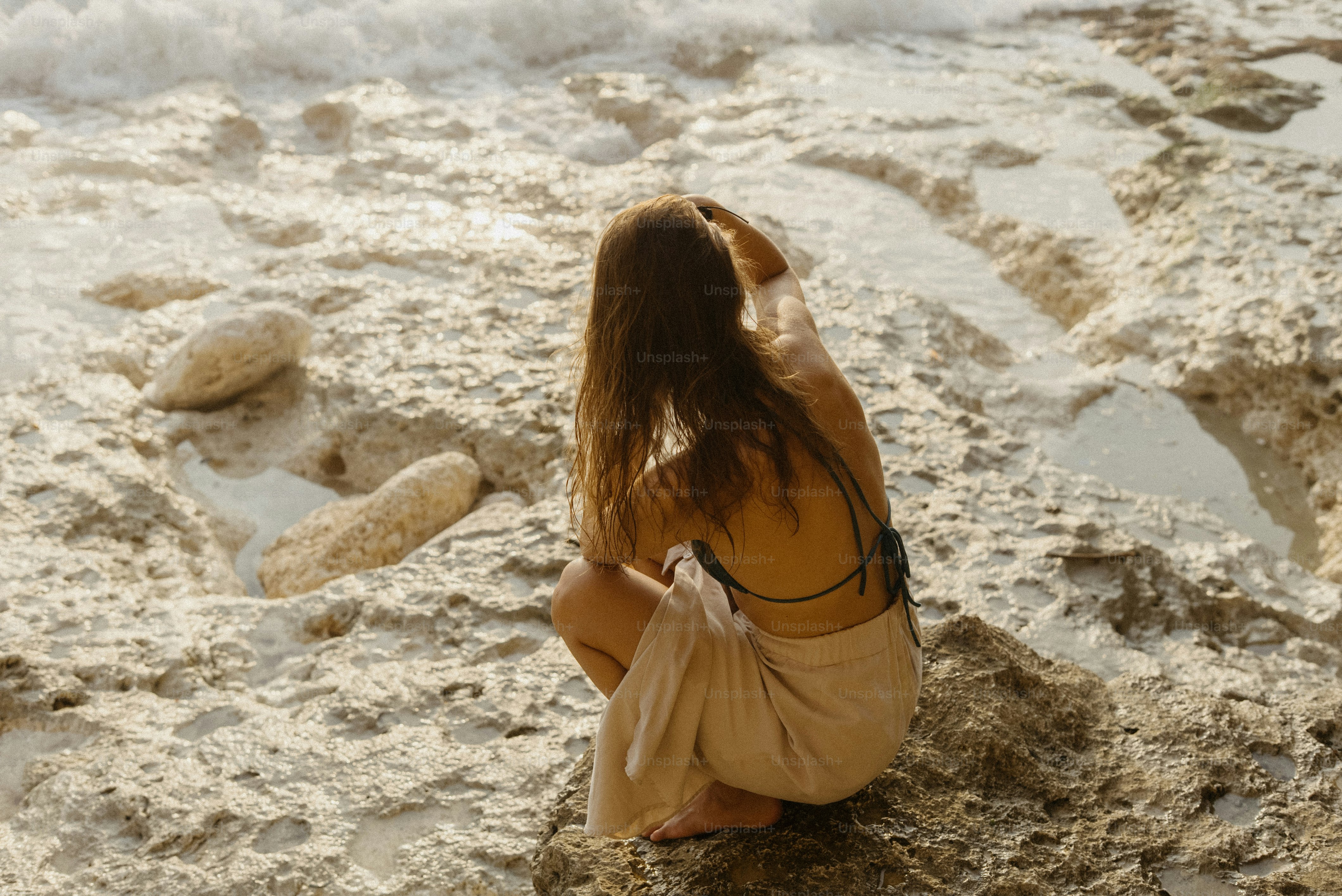 Young woman crouching on rocky beach