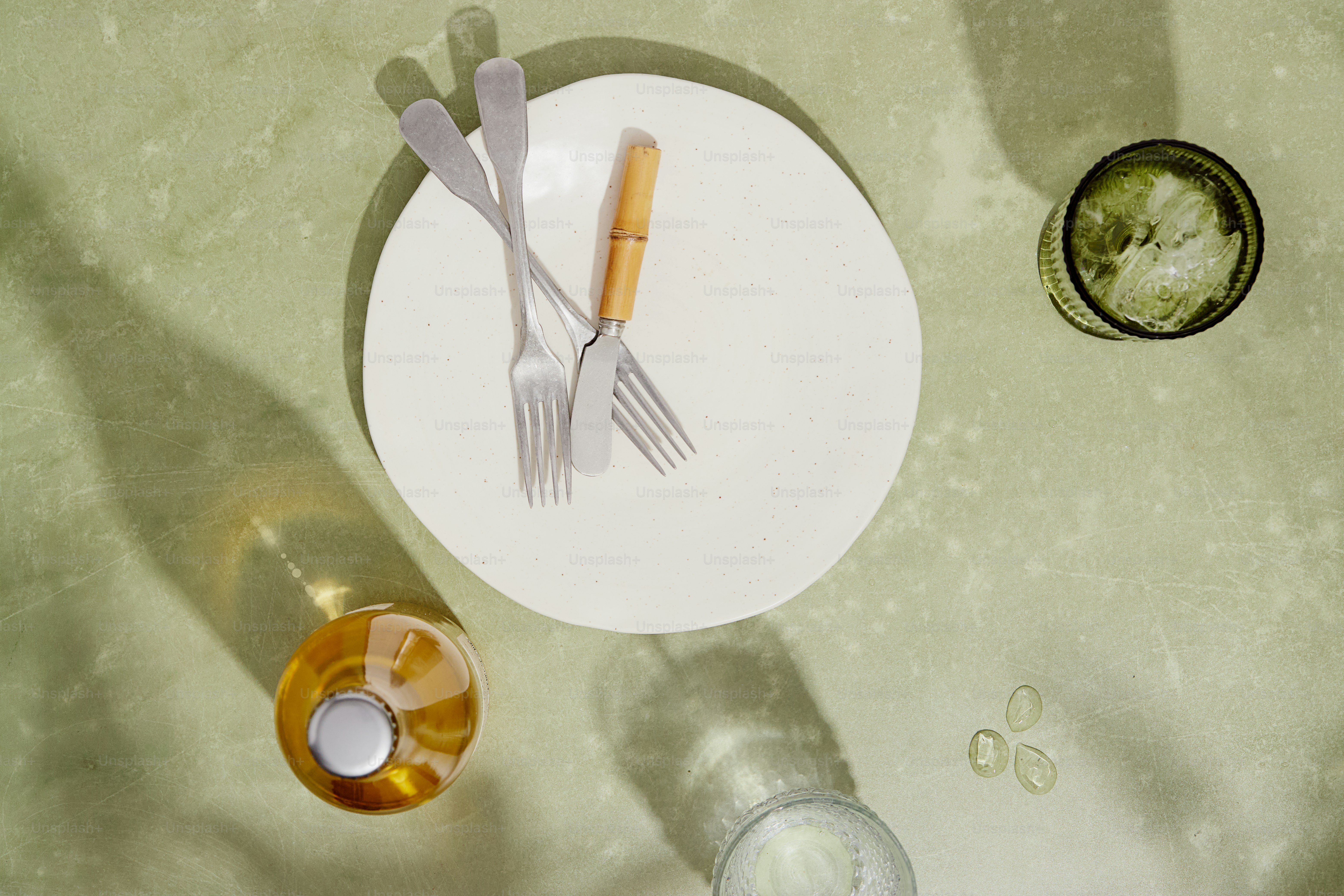 Green surface with wine bottle, plate, forks, glass