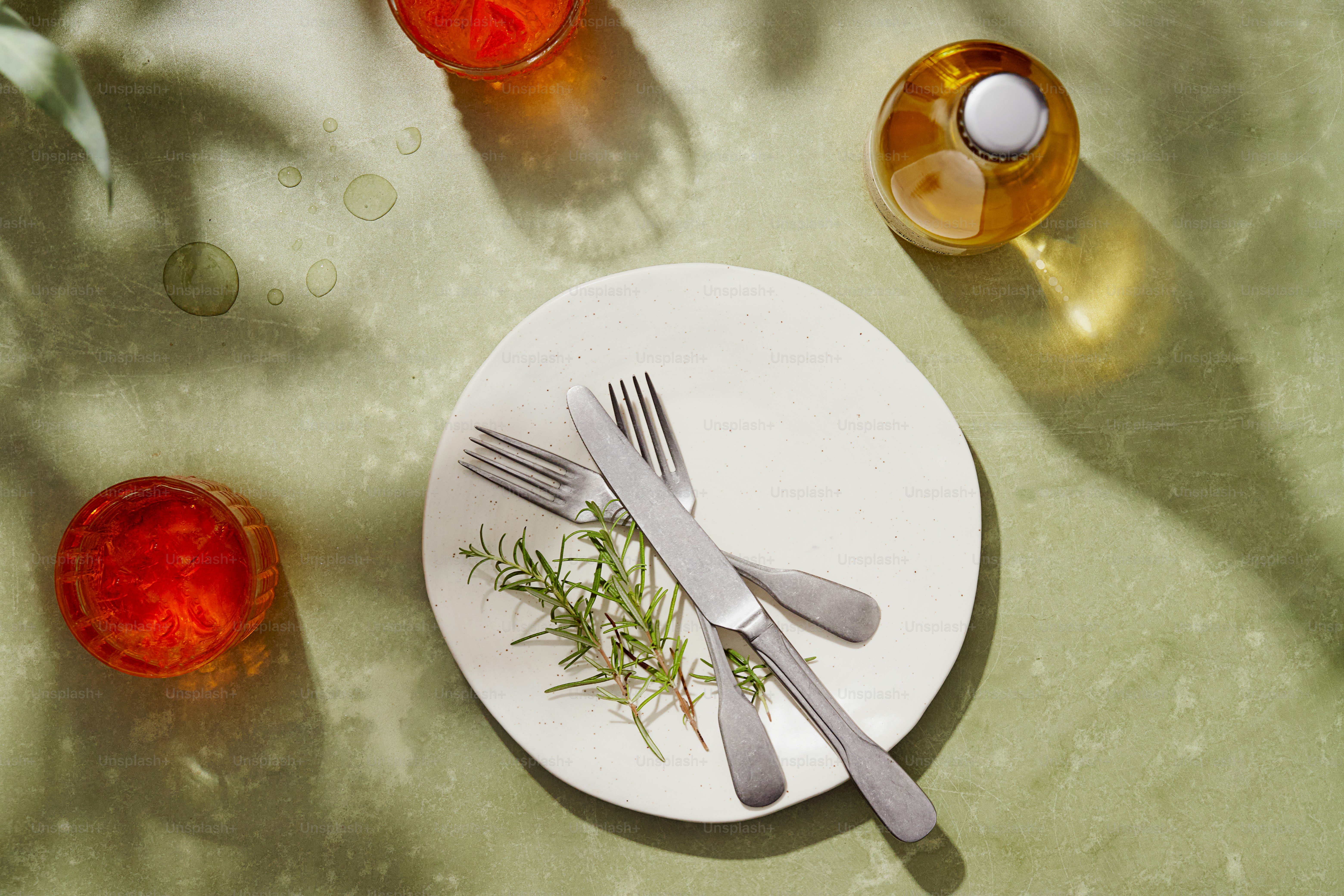 Green table setting with wine, drinks, plate, rosemary
