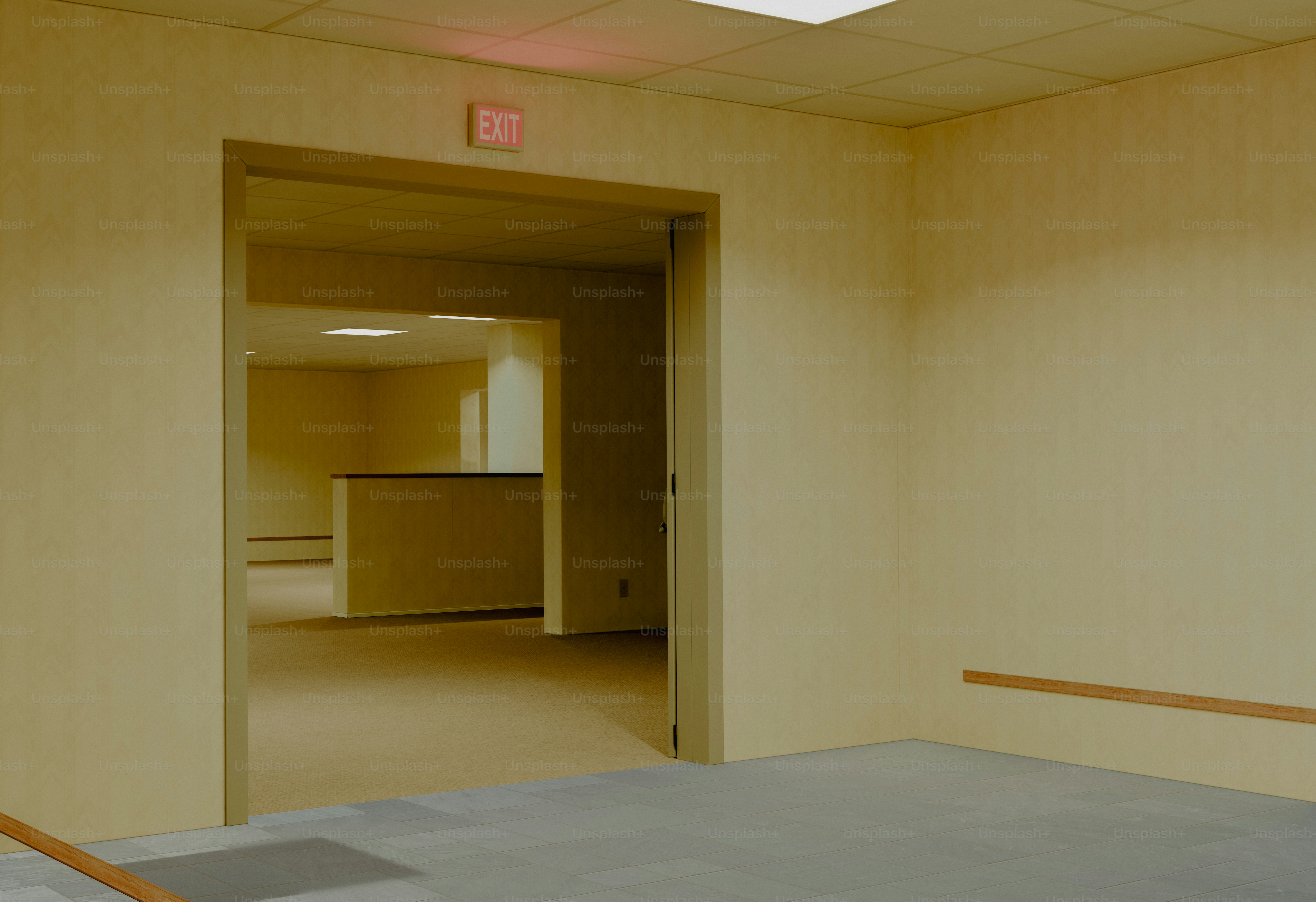Empty beige rooms with an exit sign