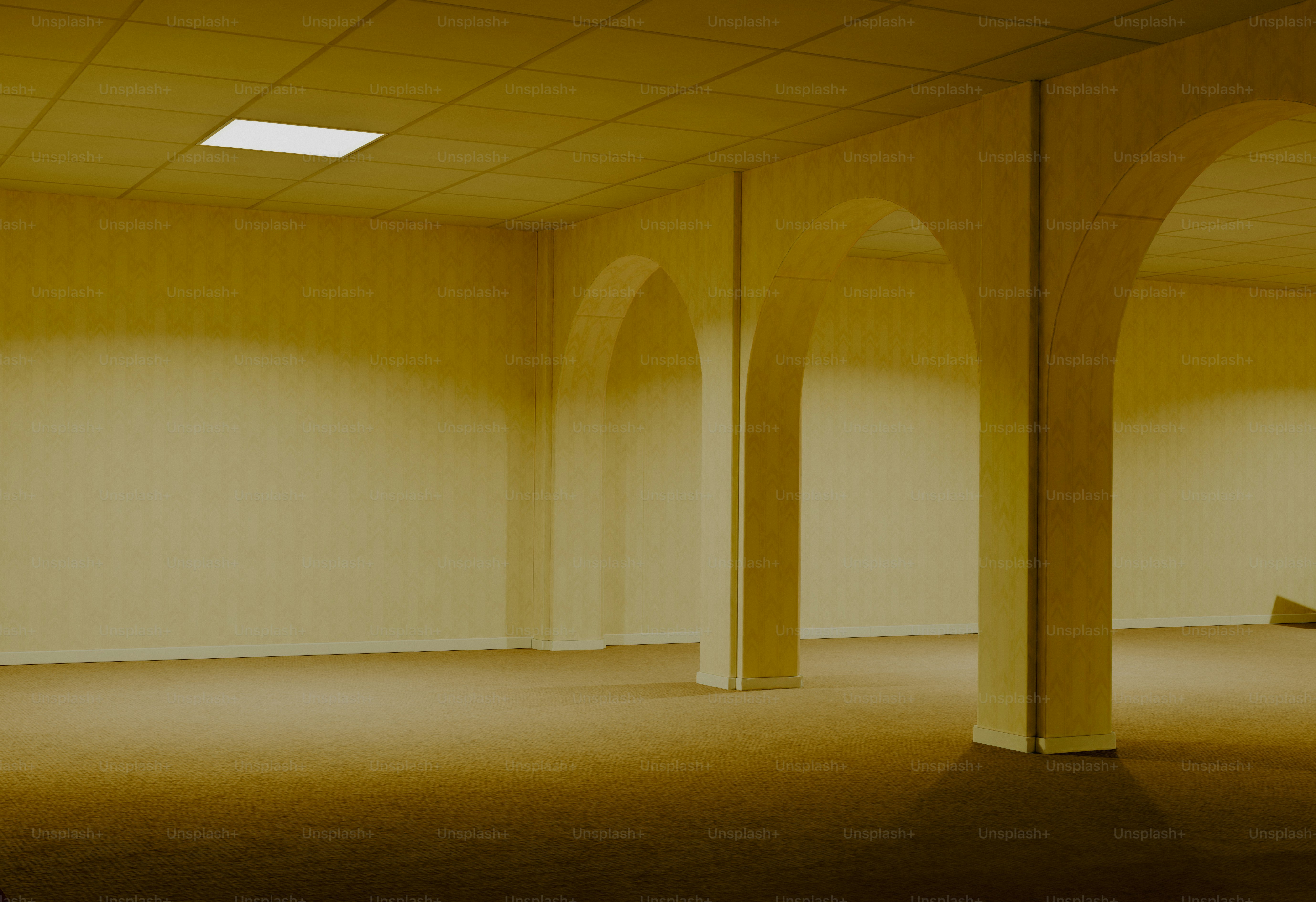 Empty yellow room with arched columns and single light