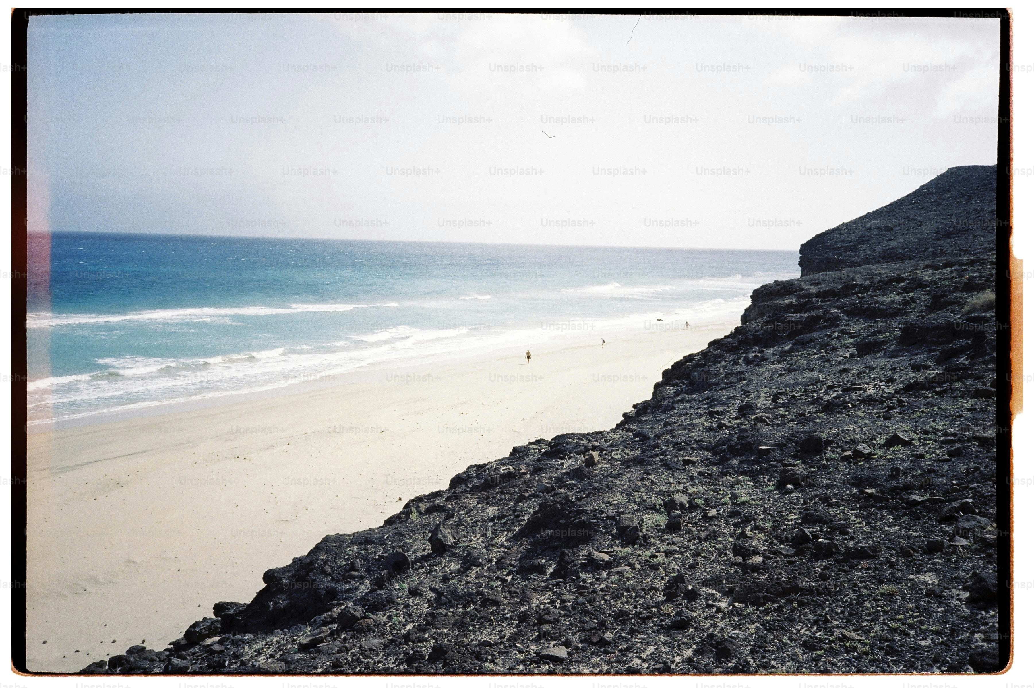 Rocky cliff overlooking a sandy beach and ocean waves