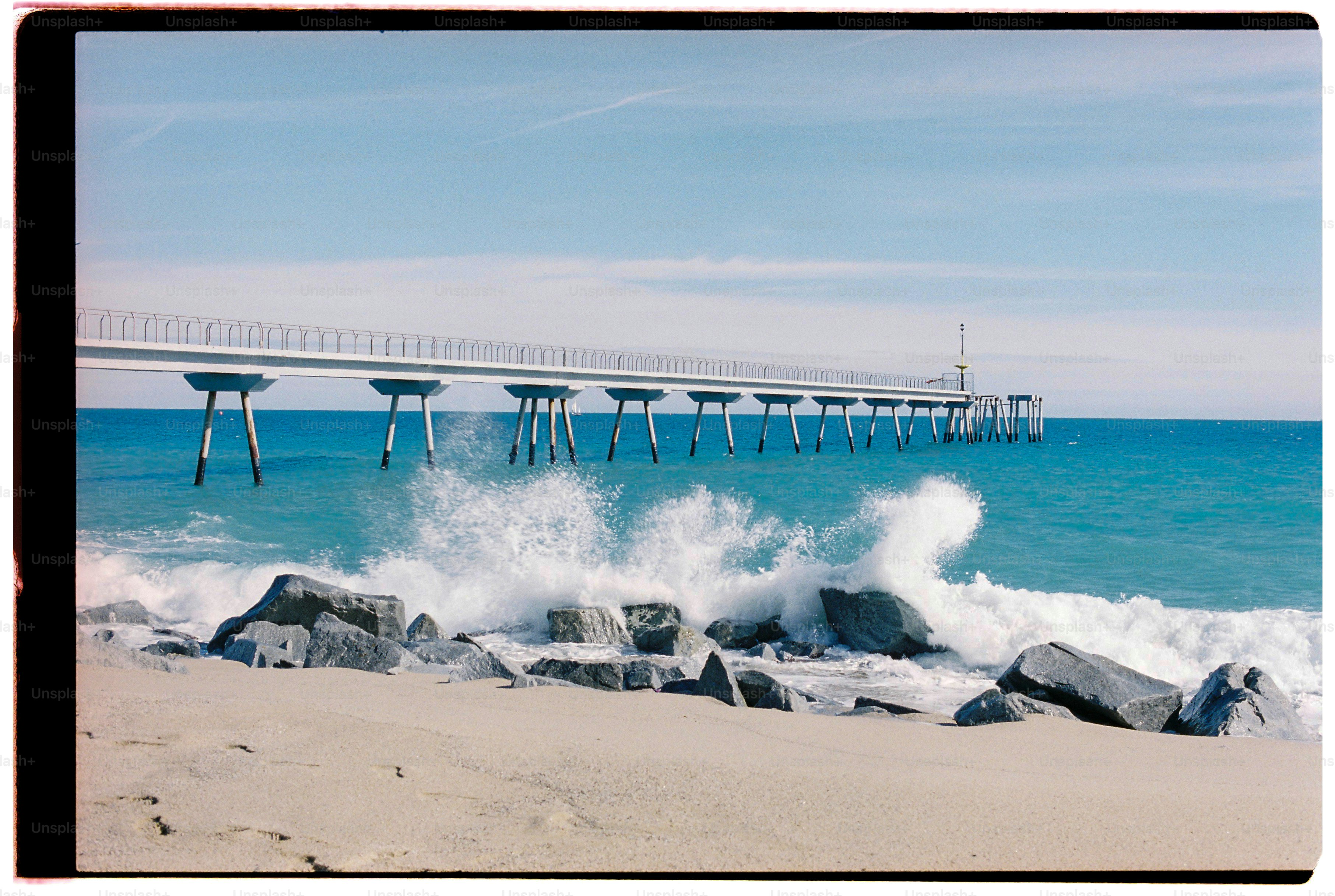 Ocean waves crashing on sandy beach near pier