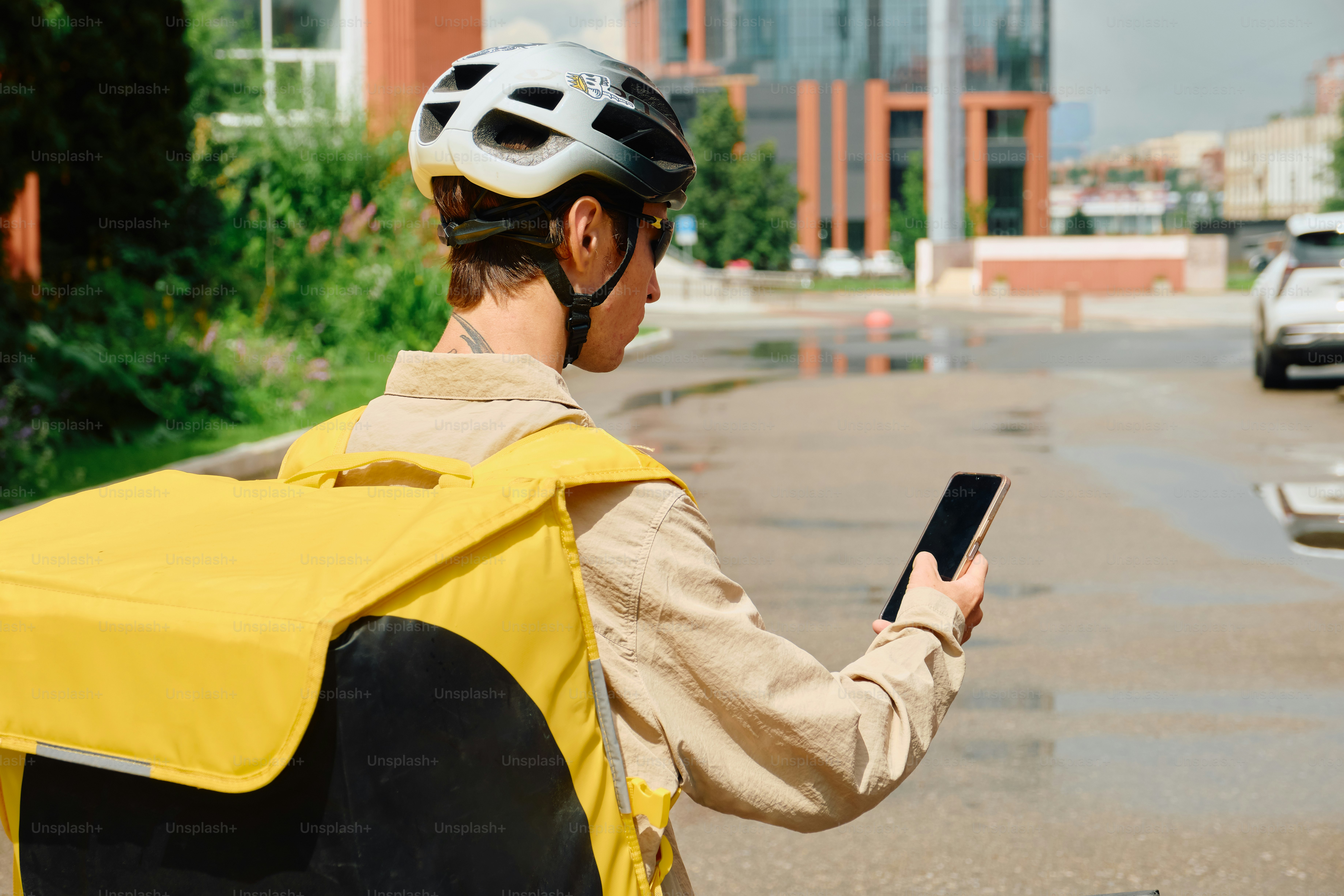 Food delivery rider checking phone on city street