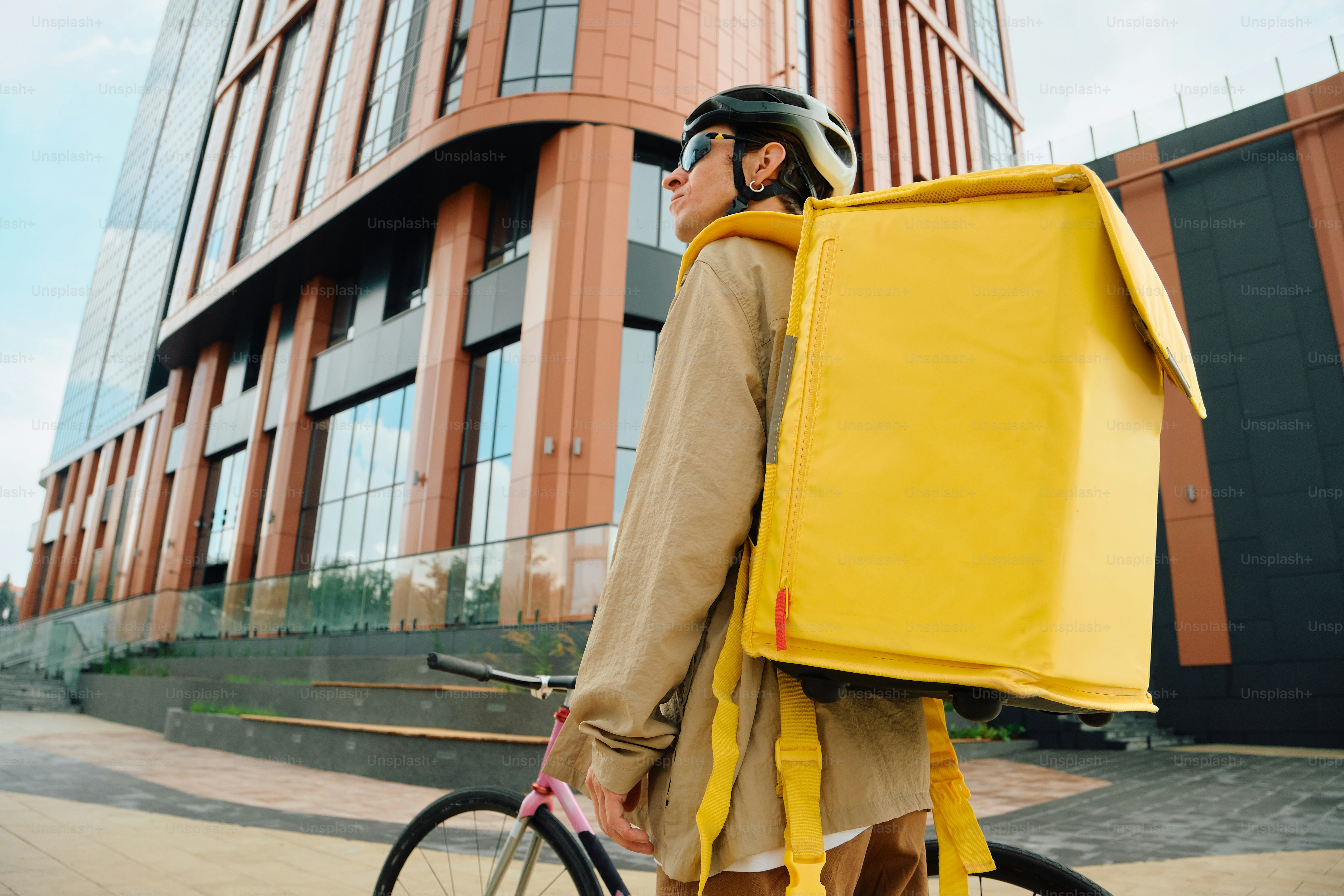 Food delivery rider with yellow backpack in city