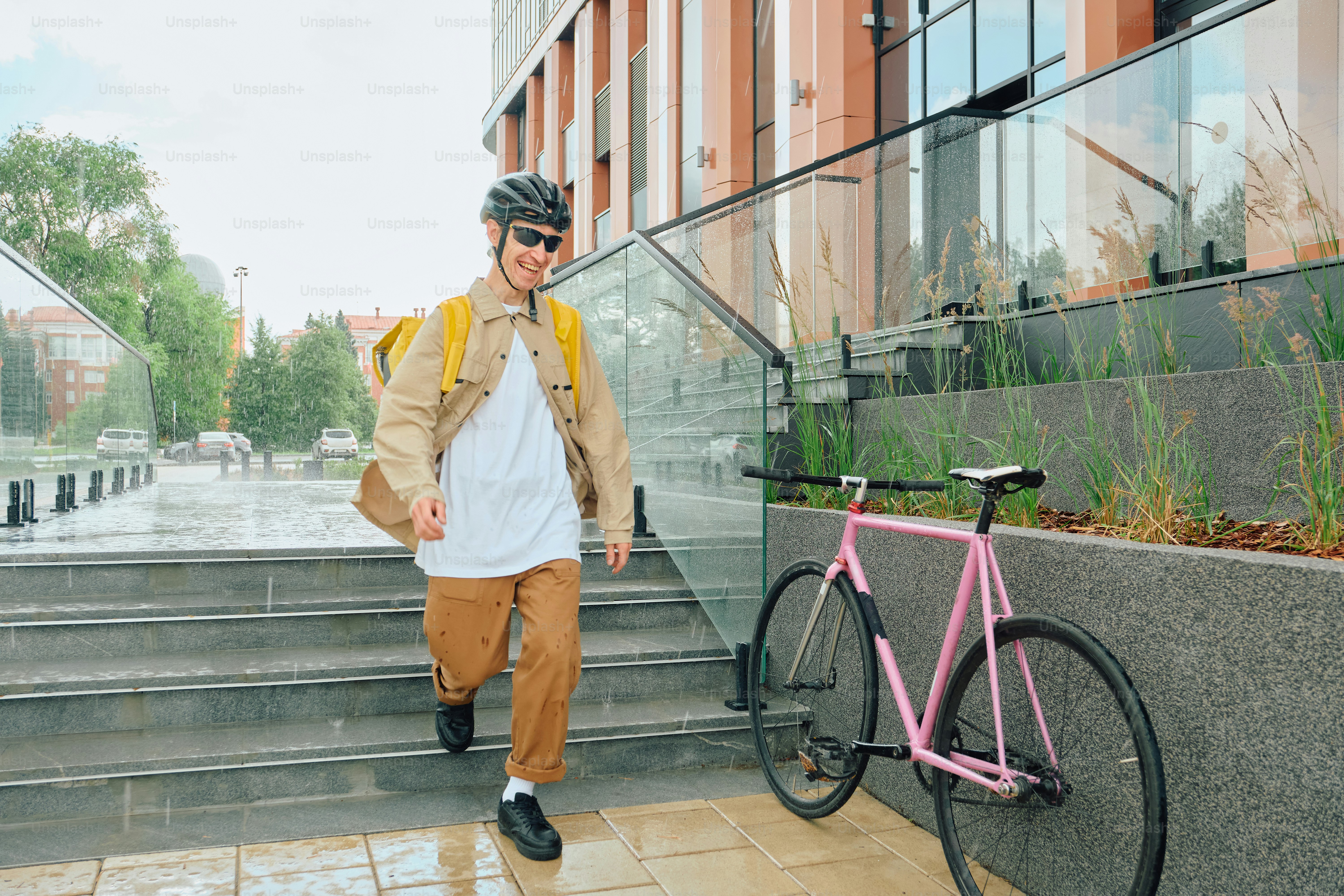Smiling food delivery rider descends city stairs beside bike