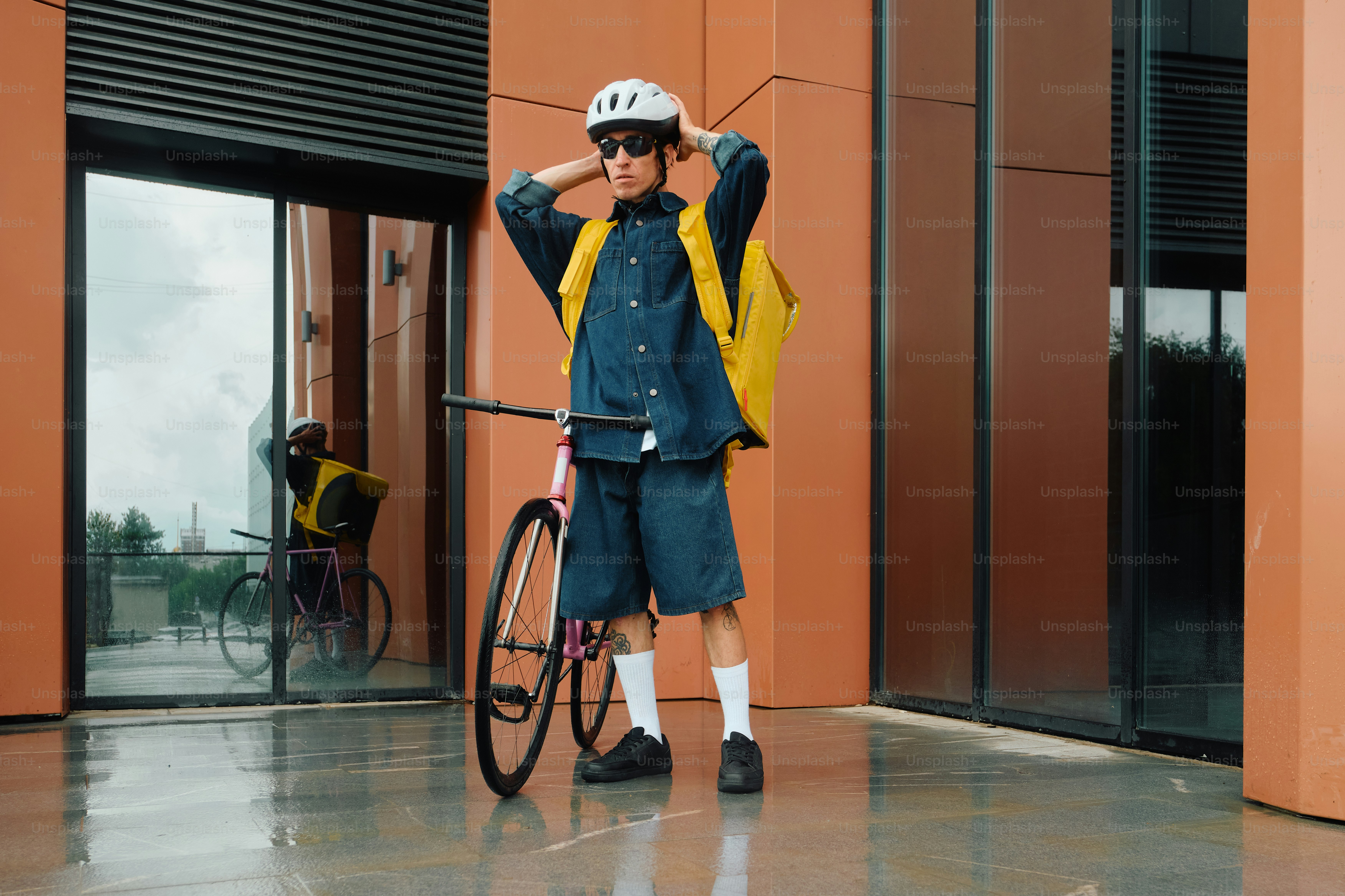 Food delivery rider adjusting helmet in modern city