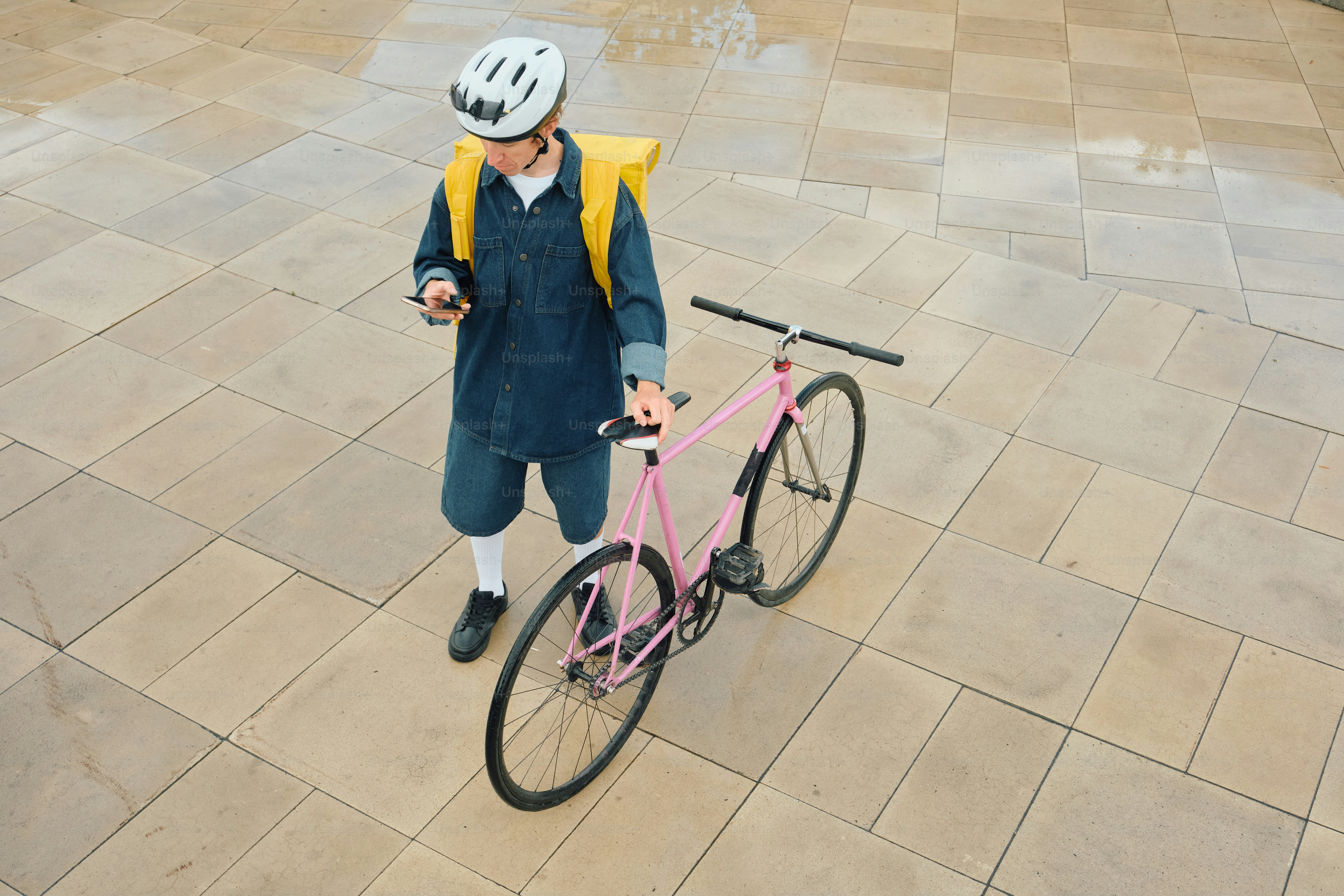Food delivery rider checking phone with pink bicycle