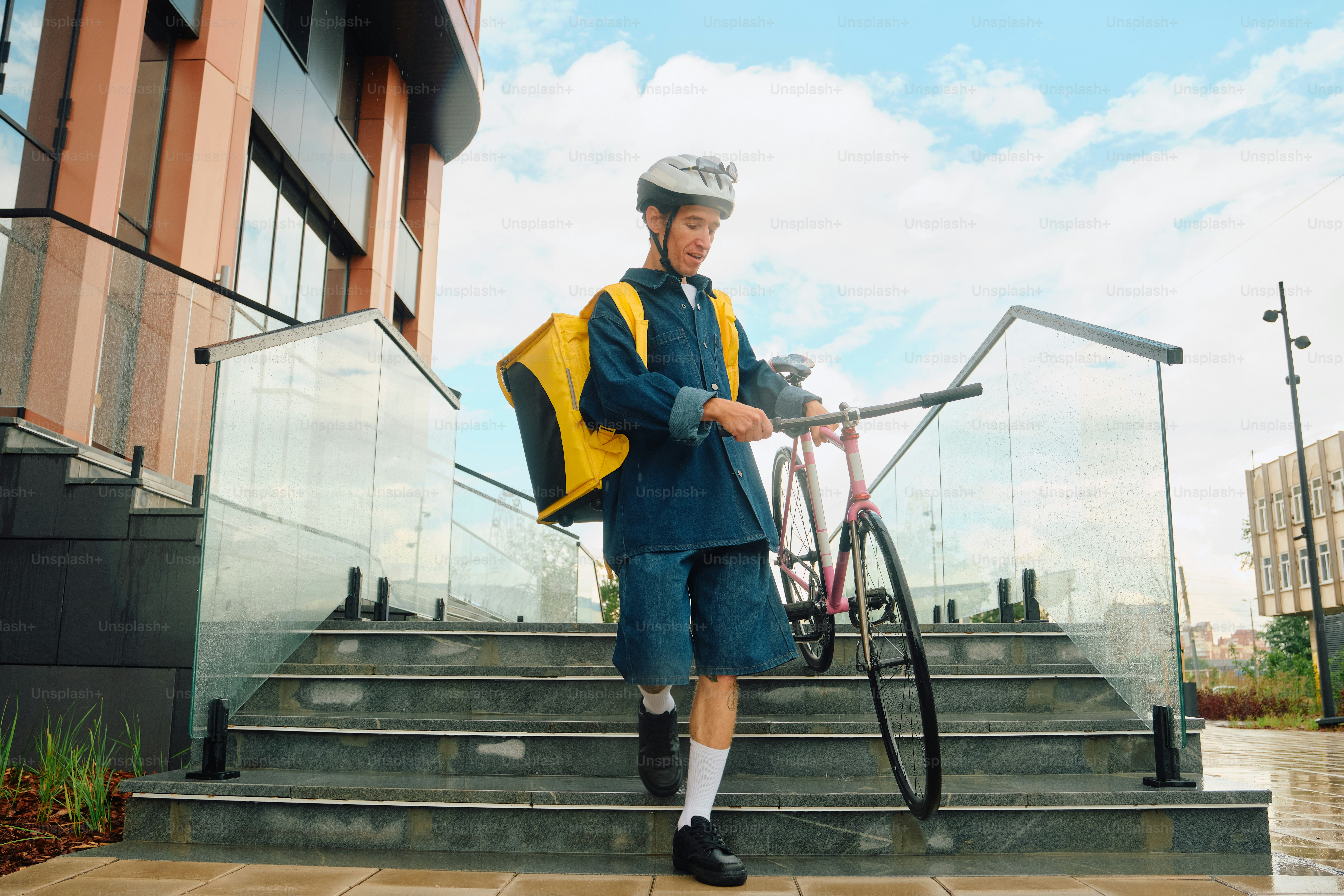 Food delivery rider walking bicycle down city stairs