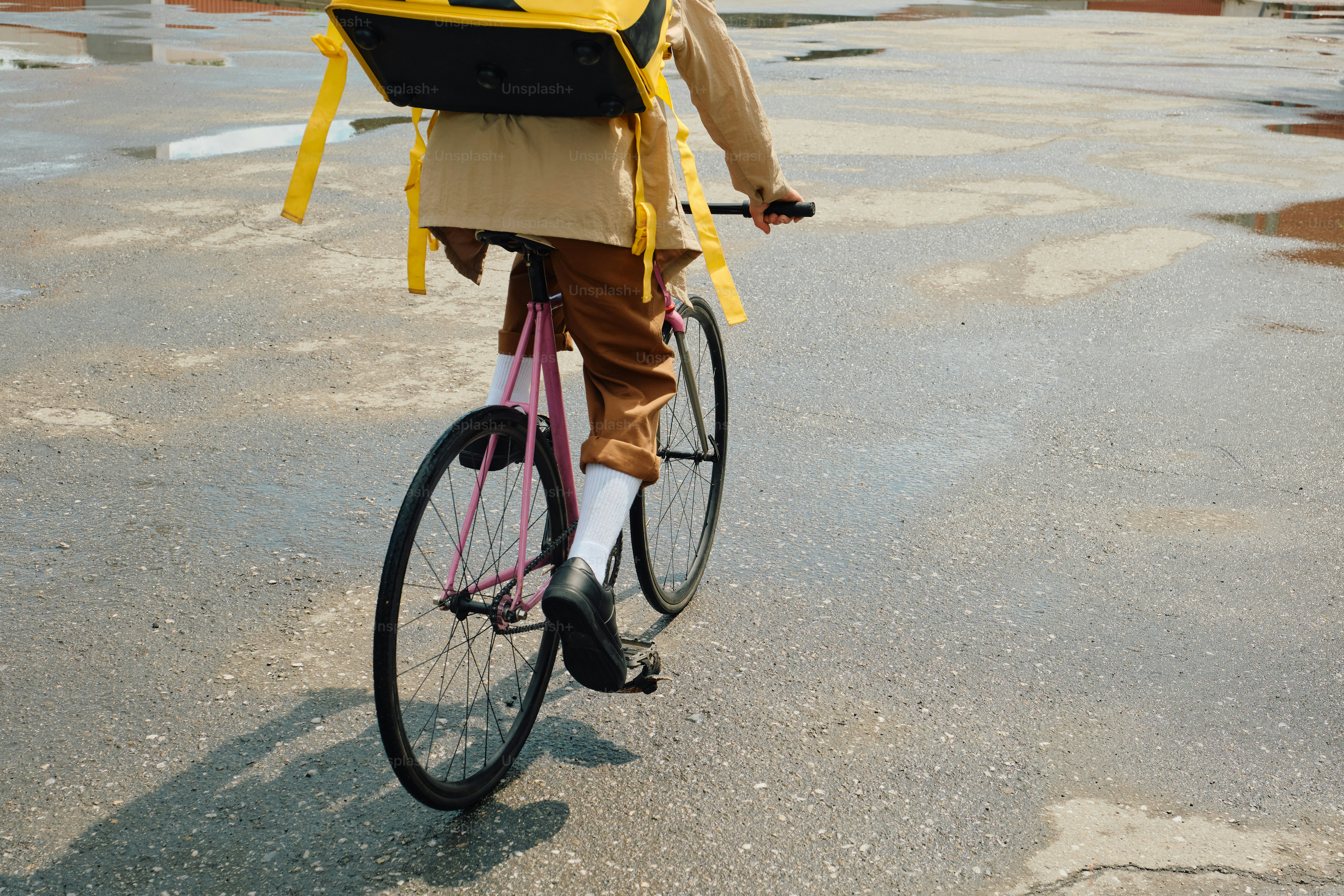 Food delivery rider cycling on wet city street
