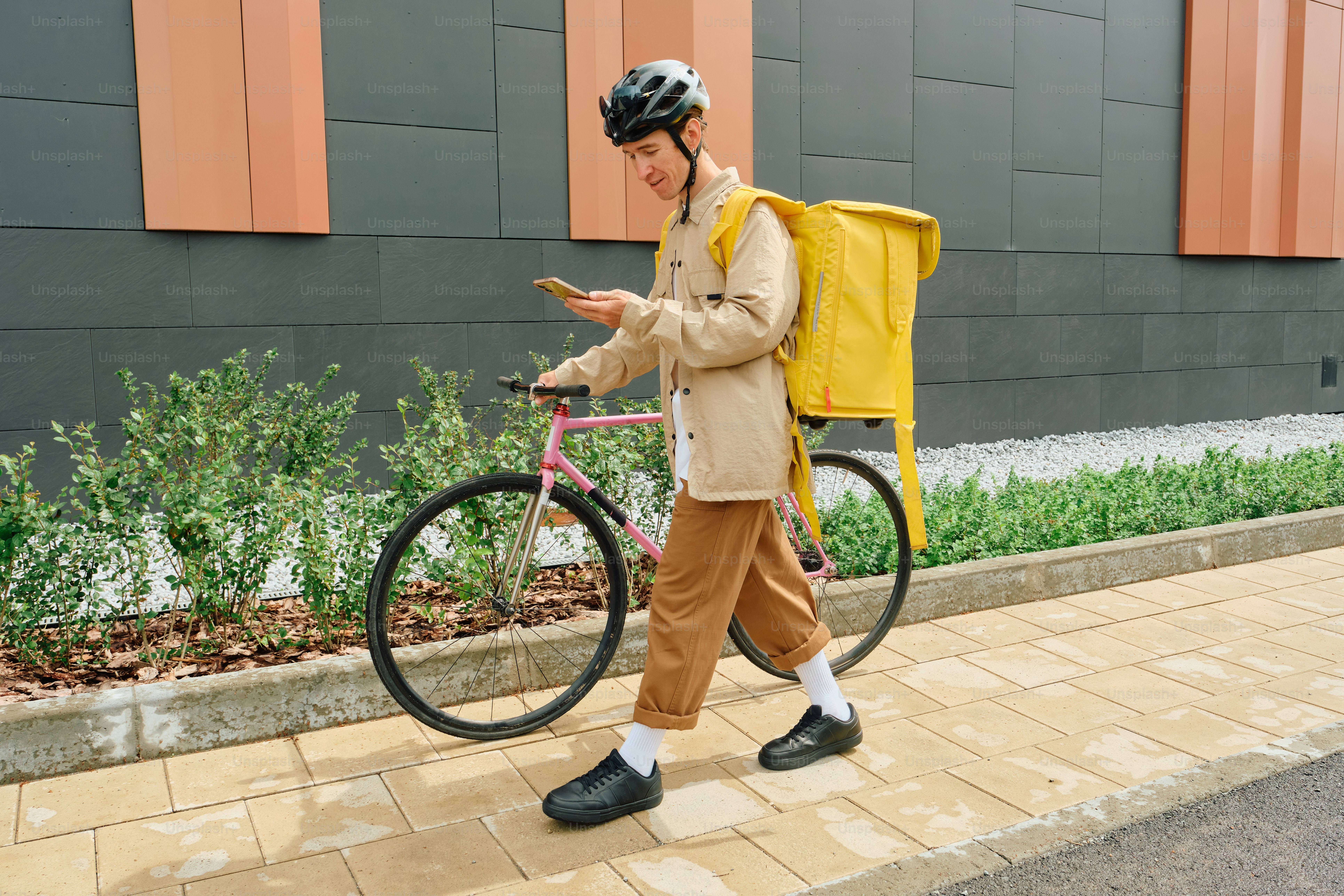 Food delivery rider with yellow bag checking phone