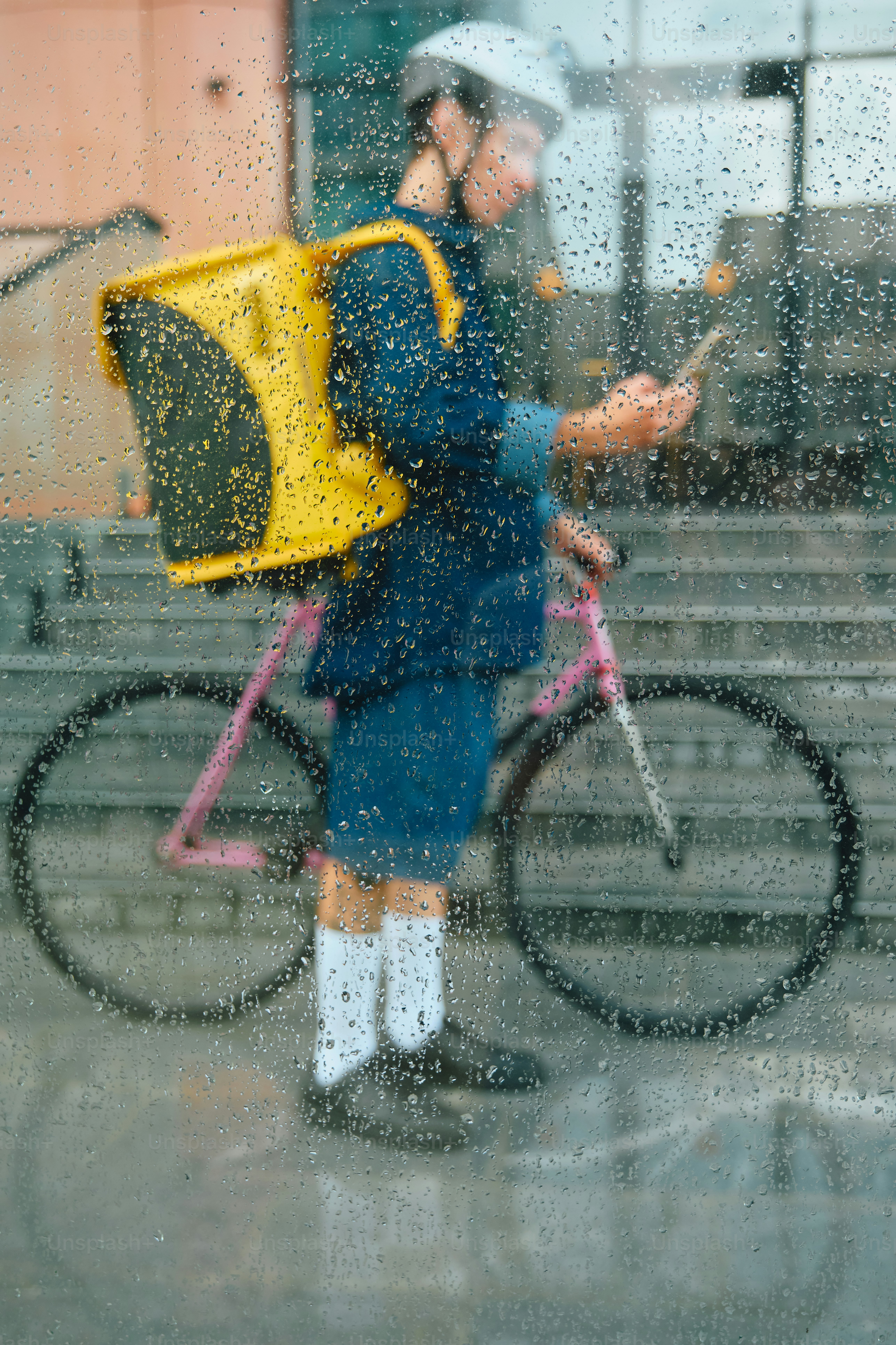 Food delivery rider checking phone in rainy city