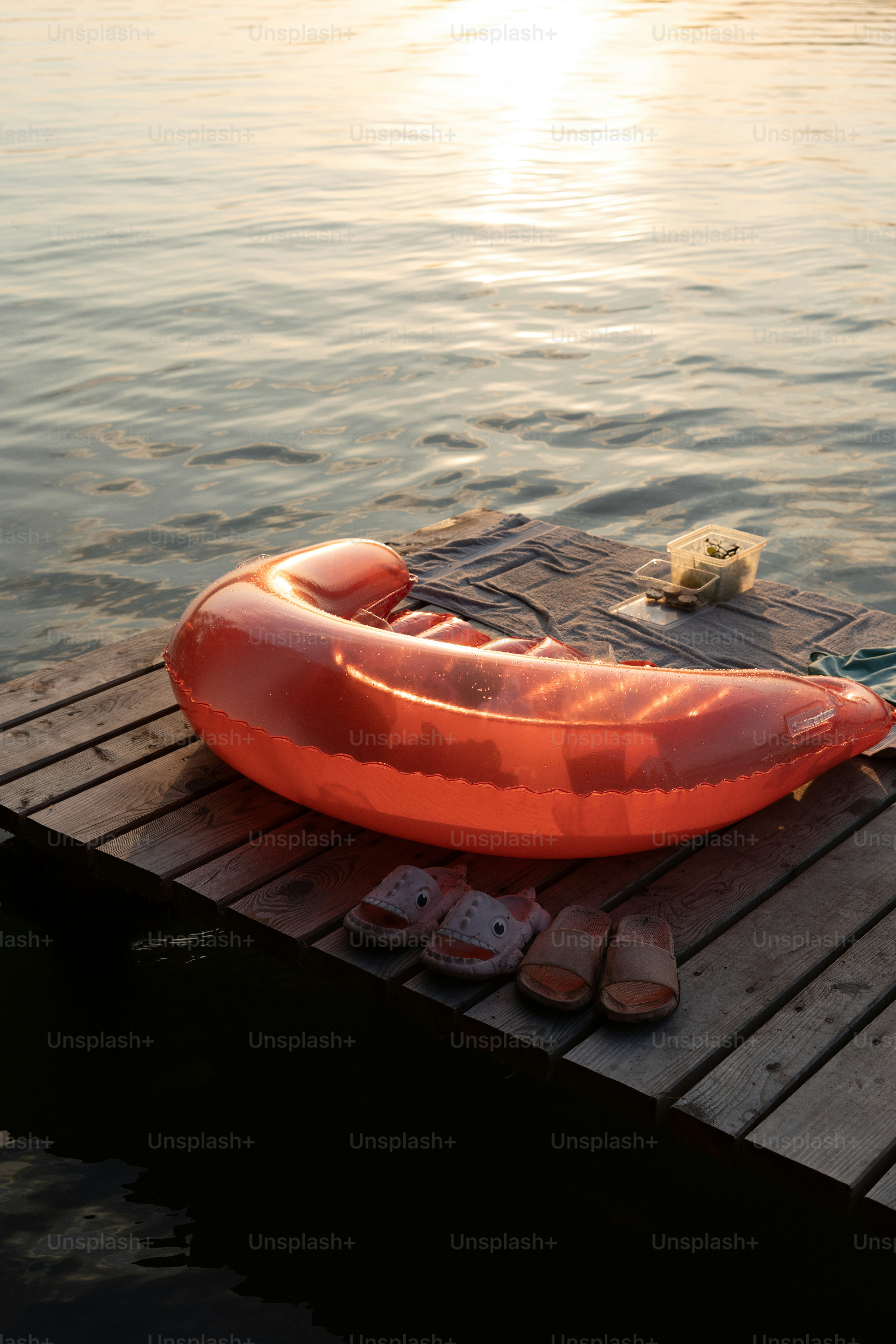 Inflatable boat and sandals on dock at sunset