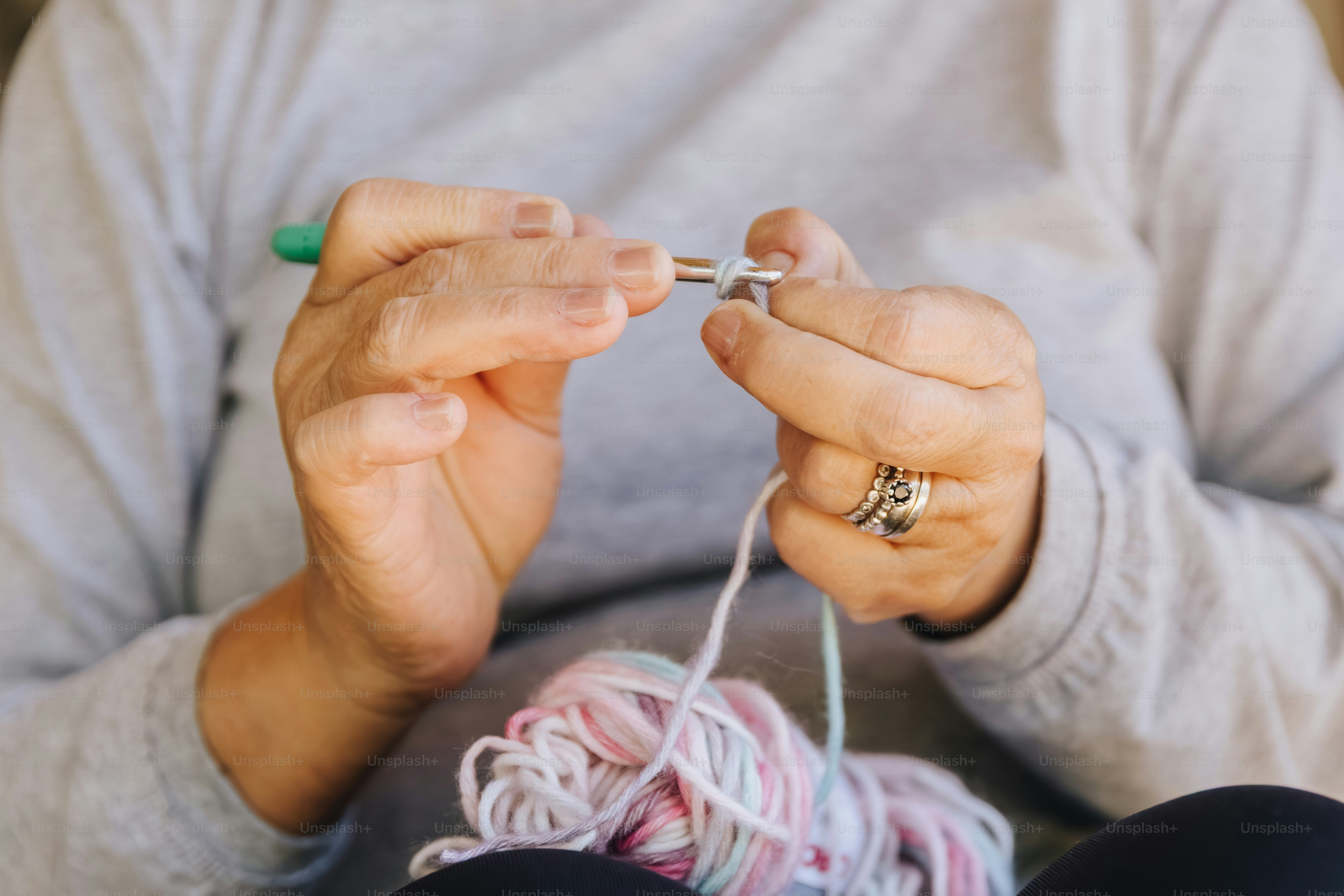 Mani che lavorano all'uncinetto con uncinetto e filato colorato