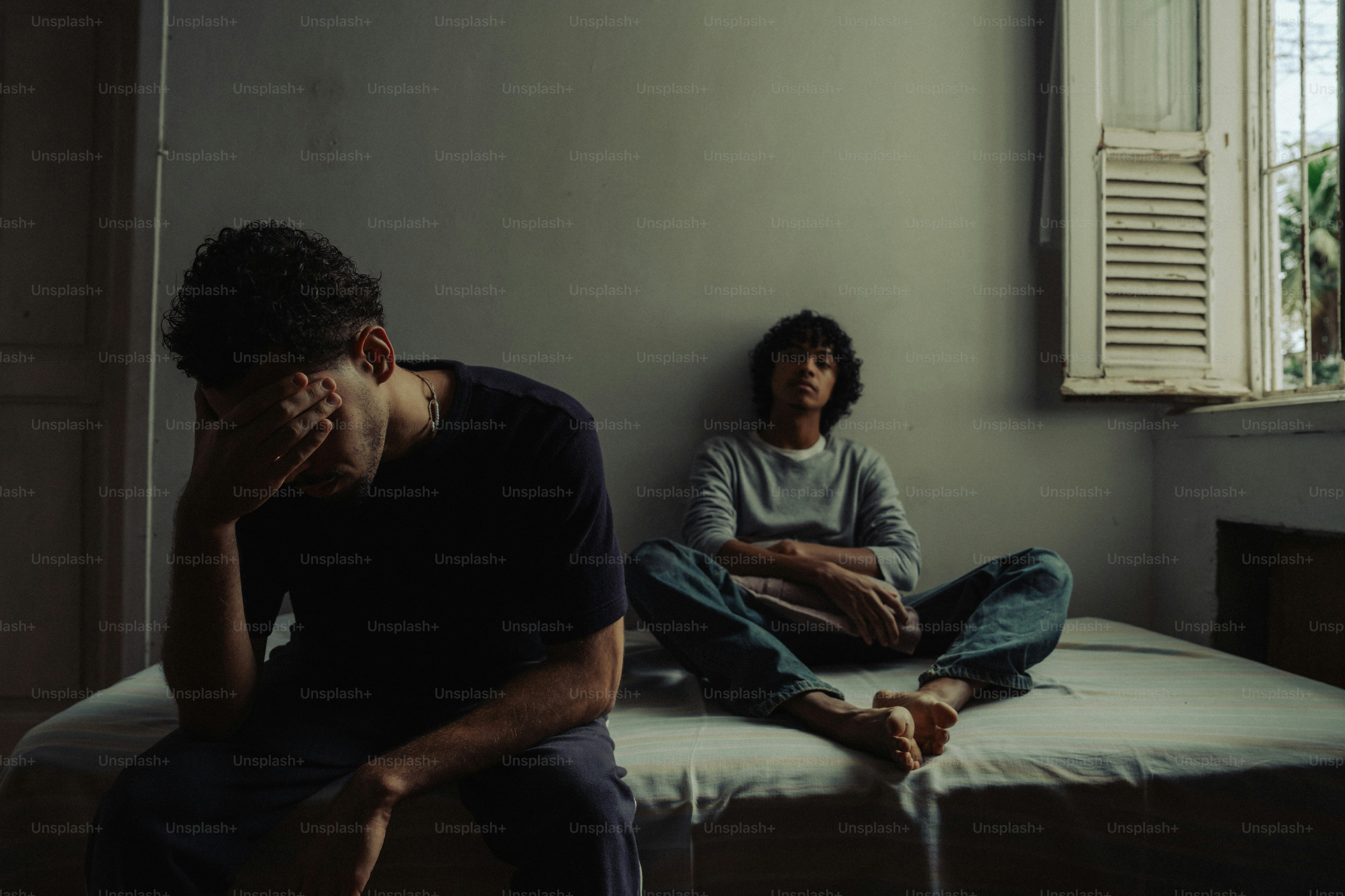 Person with head in hands, another sits separately