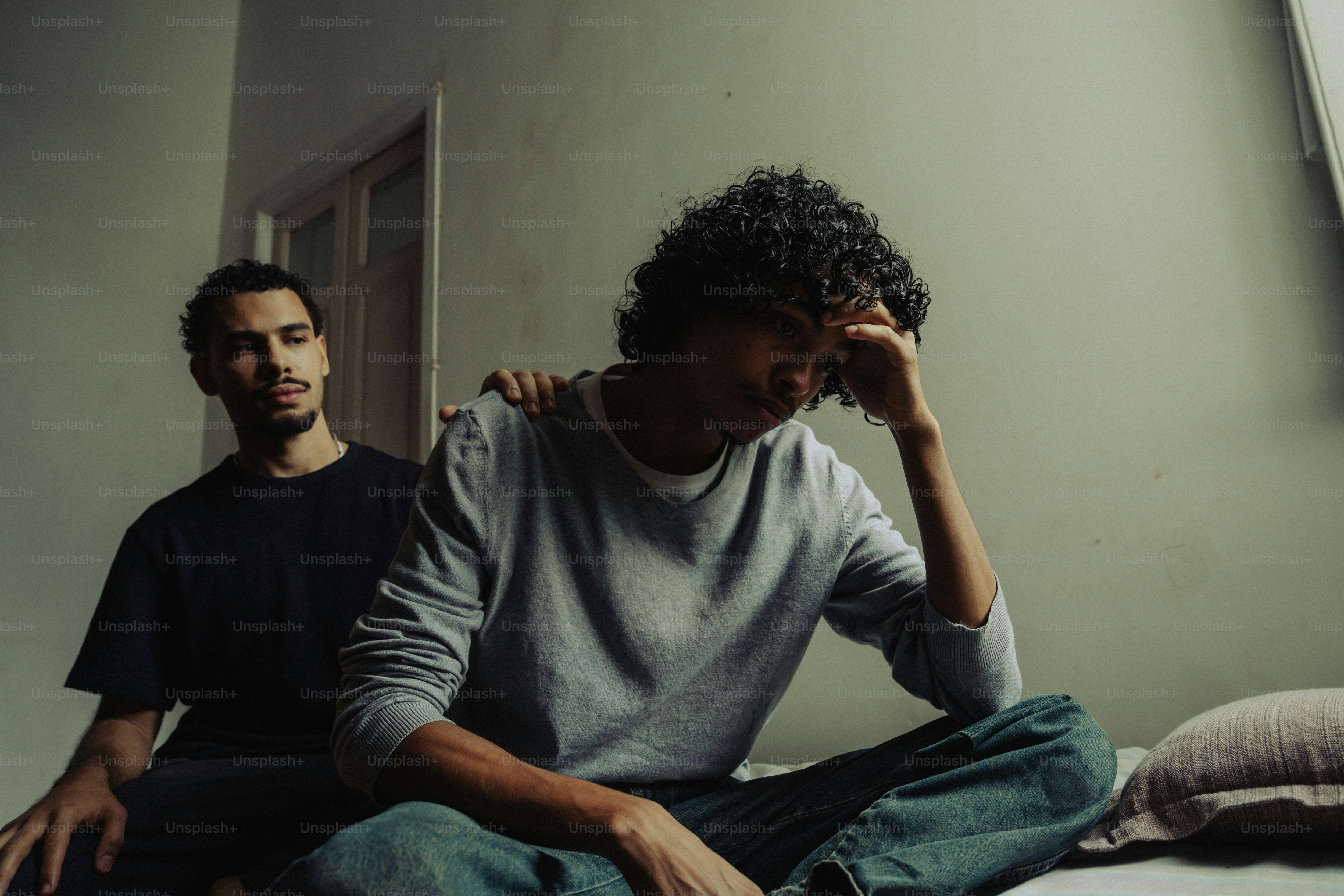 Man comforts distressed friend with hand on shoulder