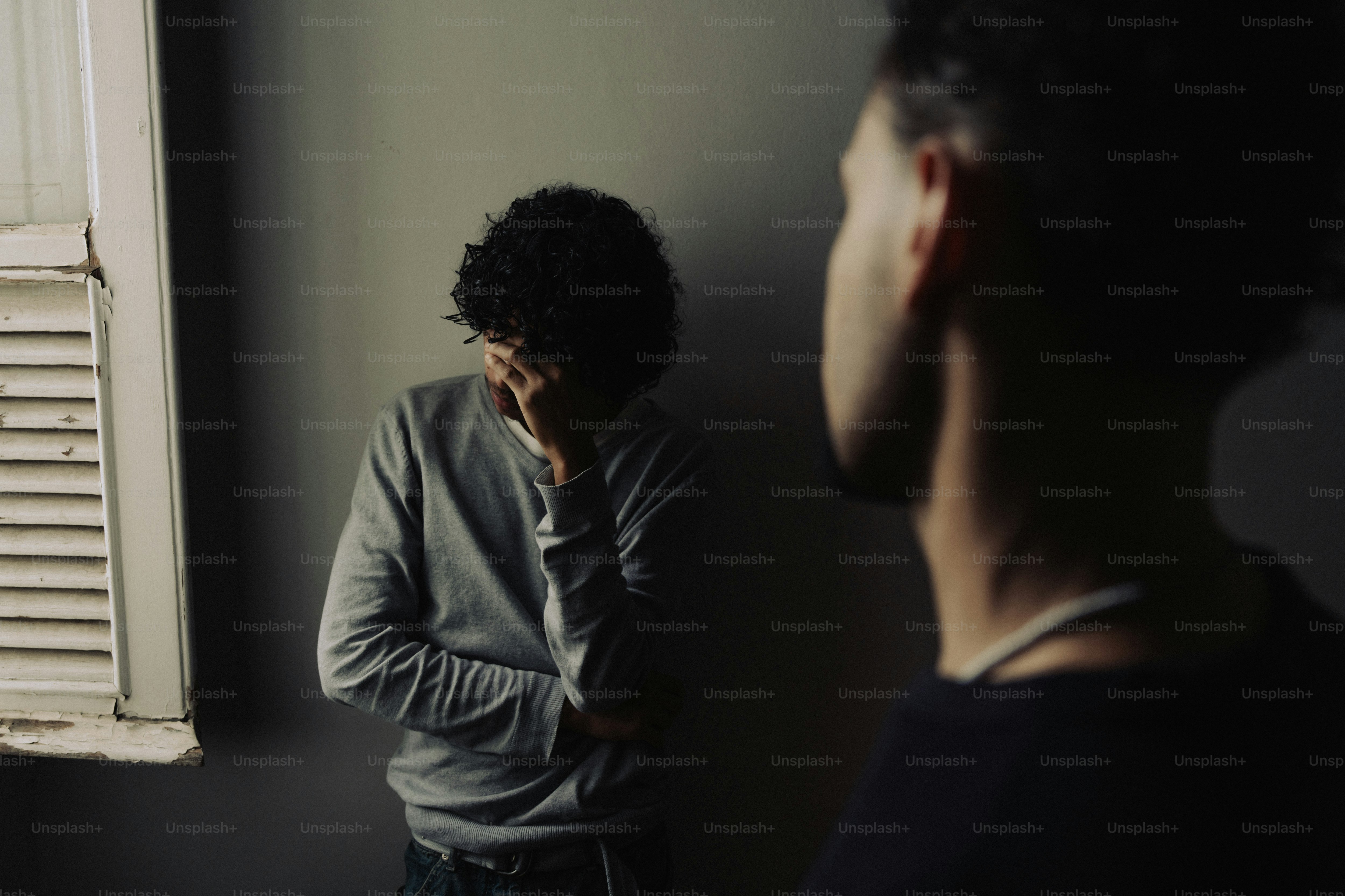 Two men, one covering face in distress