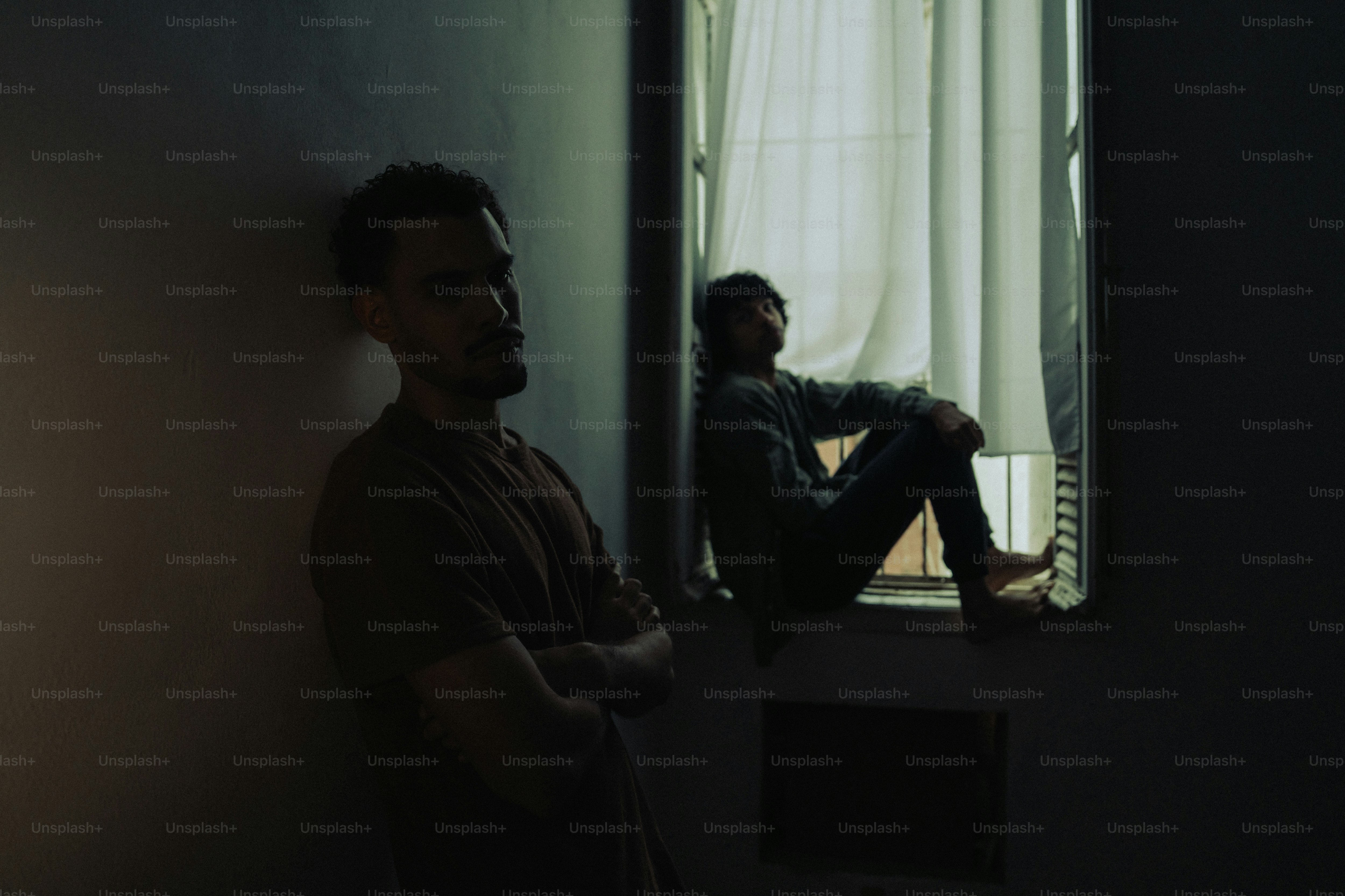 Two men in shadows, one by window