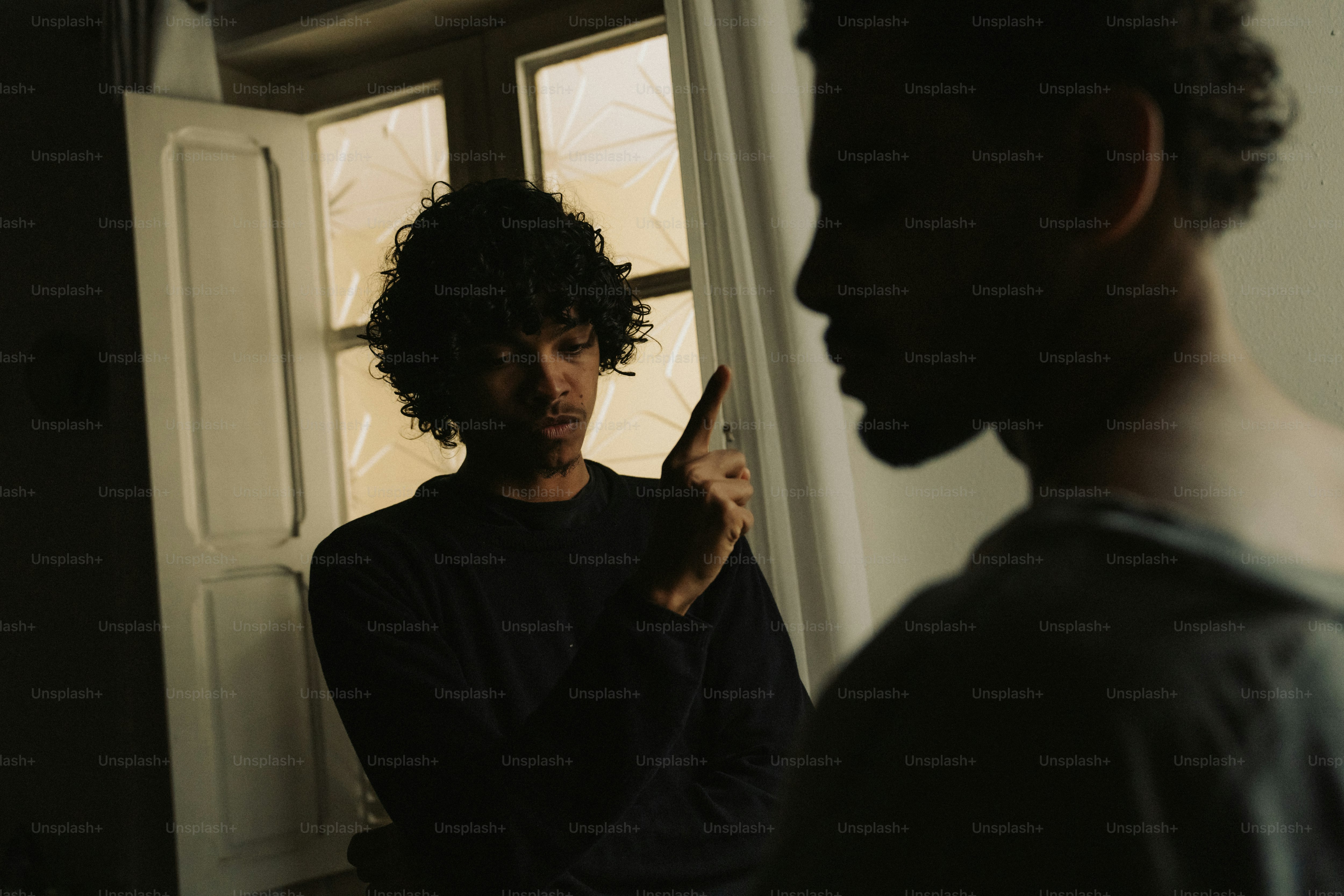 Man pointing finger at another man indoors