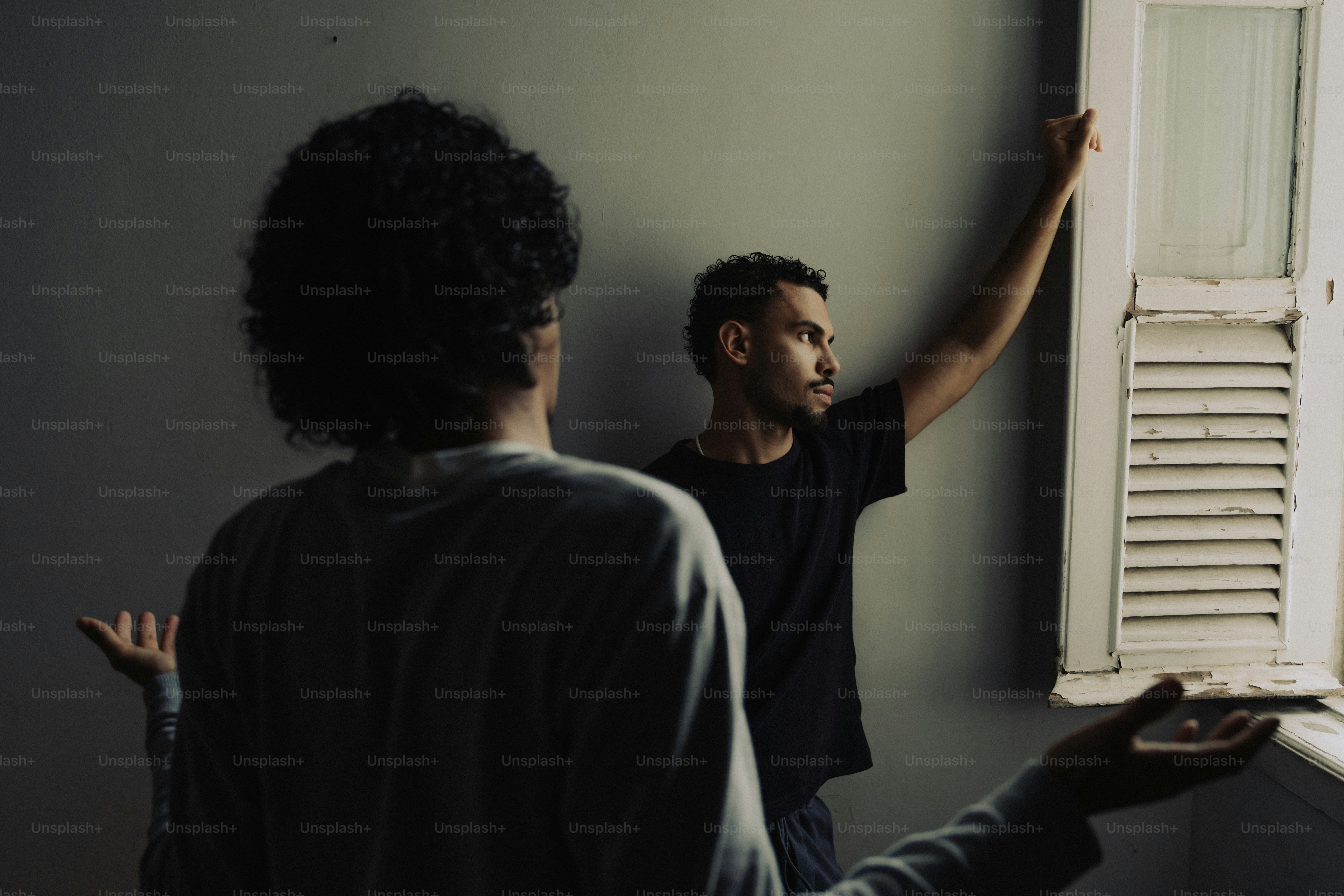 Two people by window, one looking out