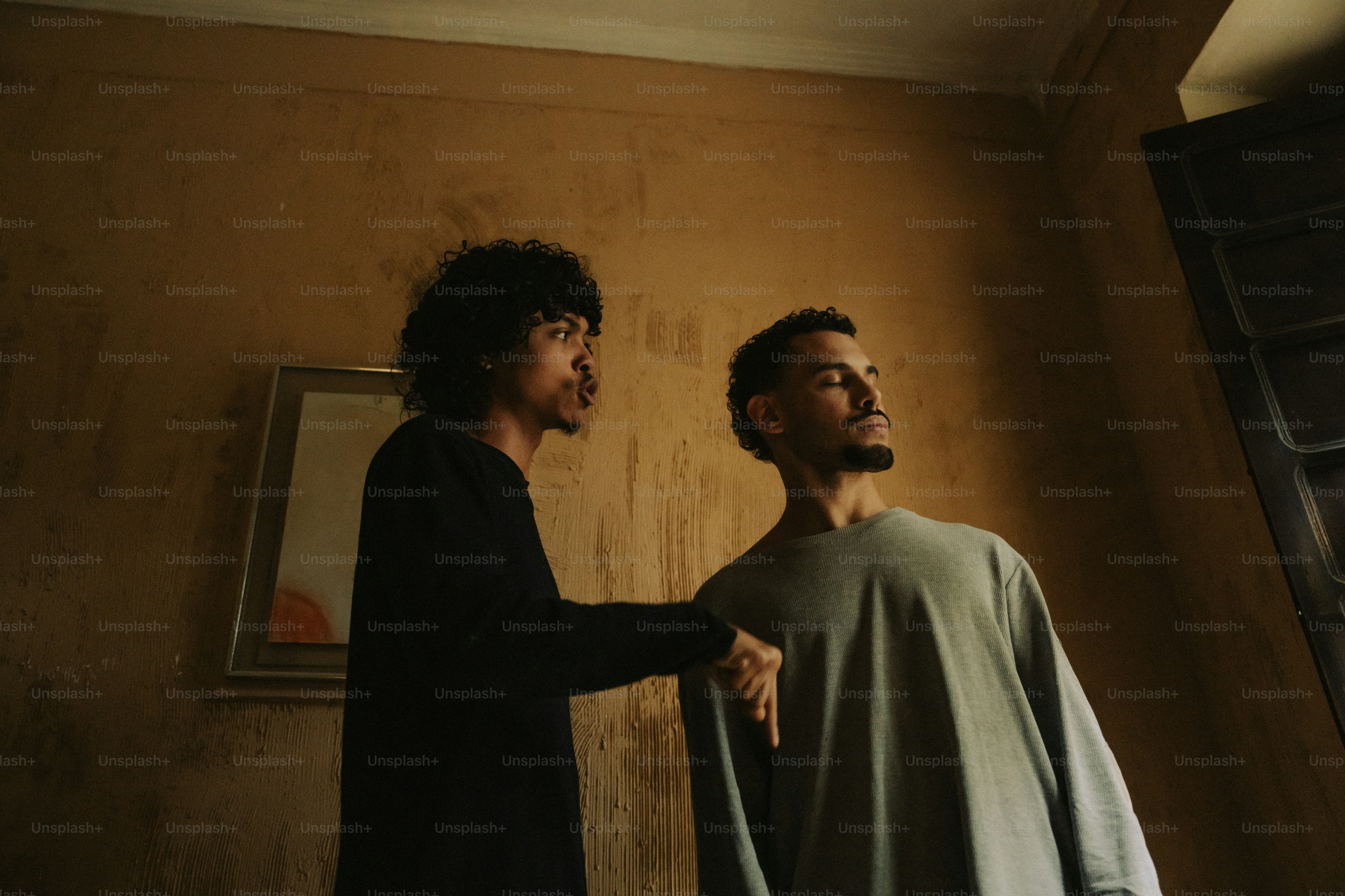 Two men in a warm-toned, dimly lit room