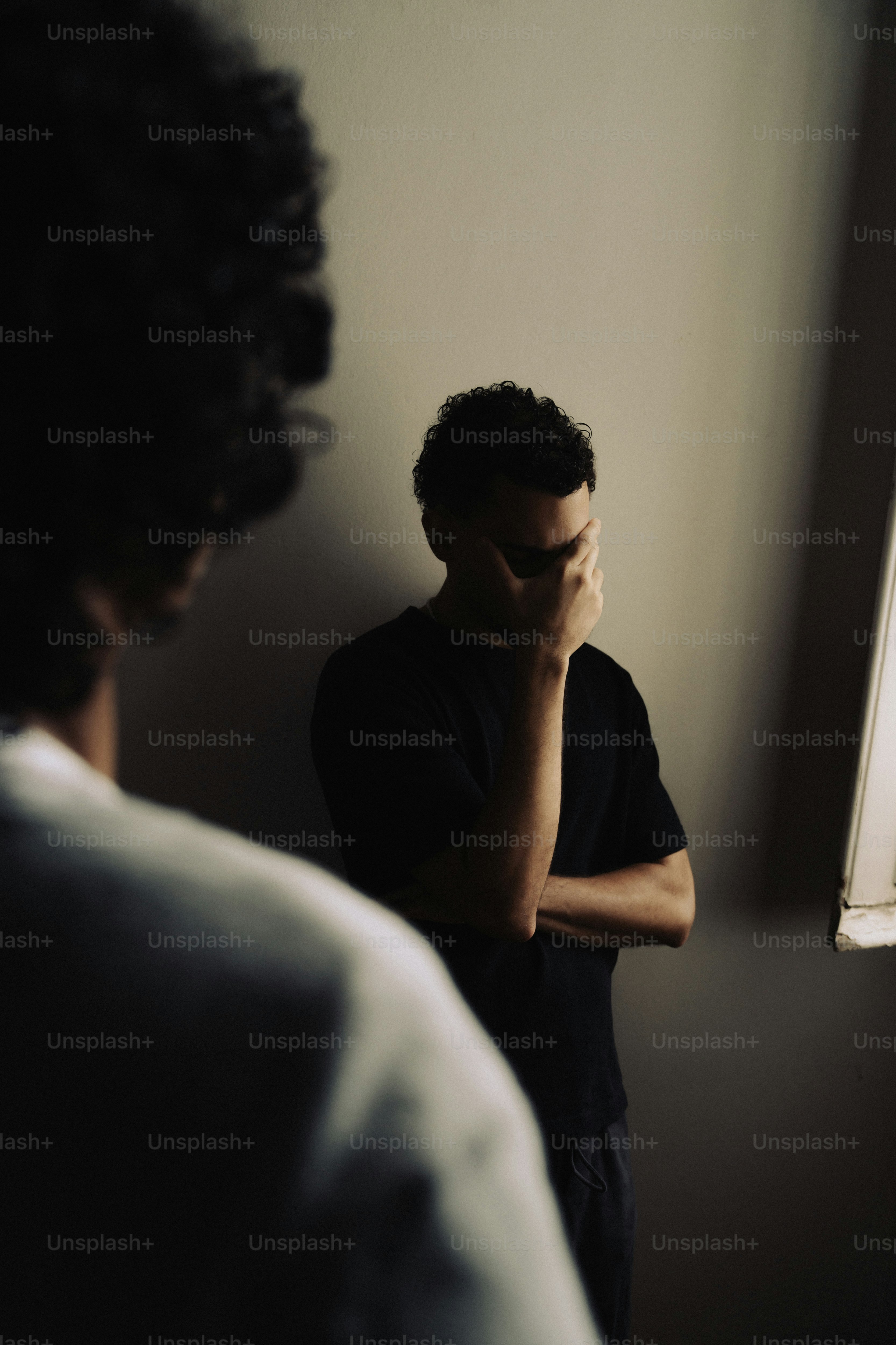 Person covering face in dimly lit room