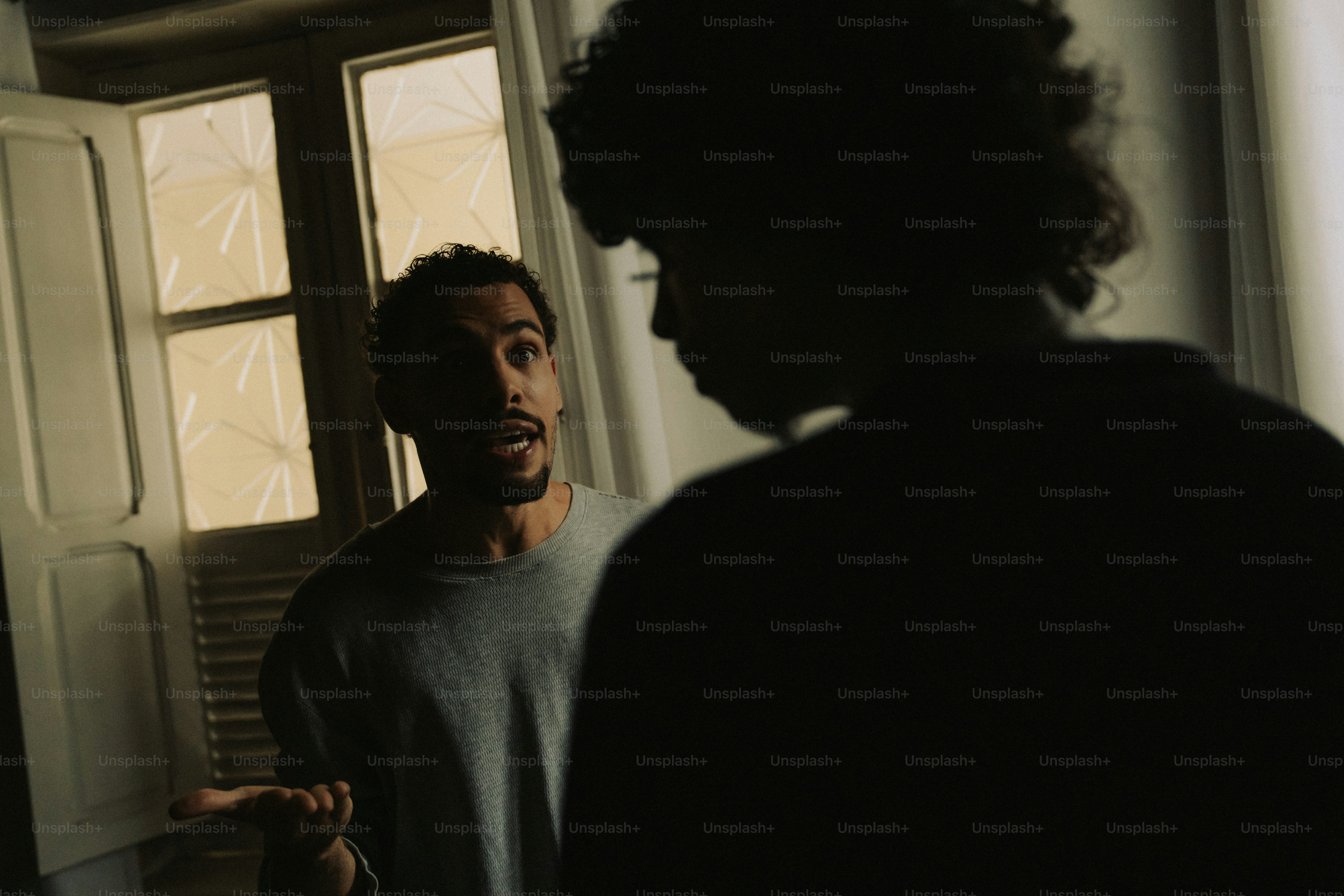 Man speaking to another person near a window
