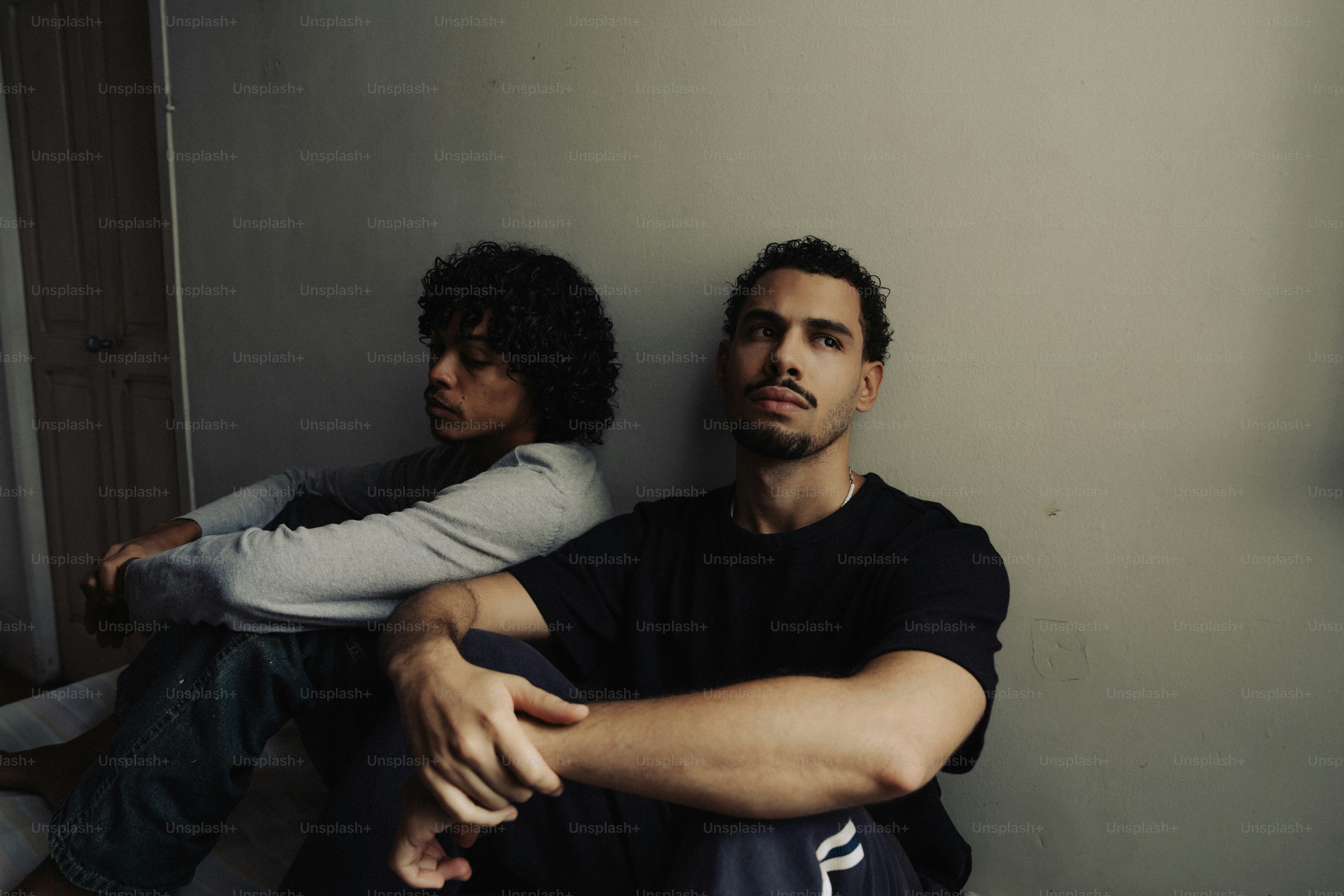 Men sitting on floor against a wall