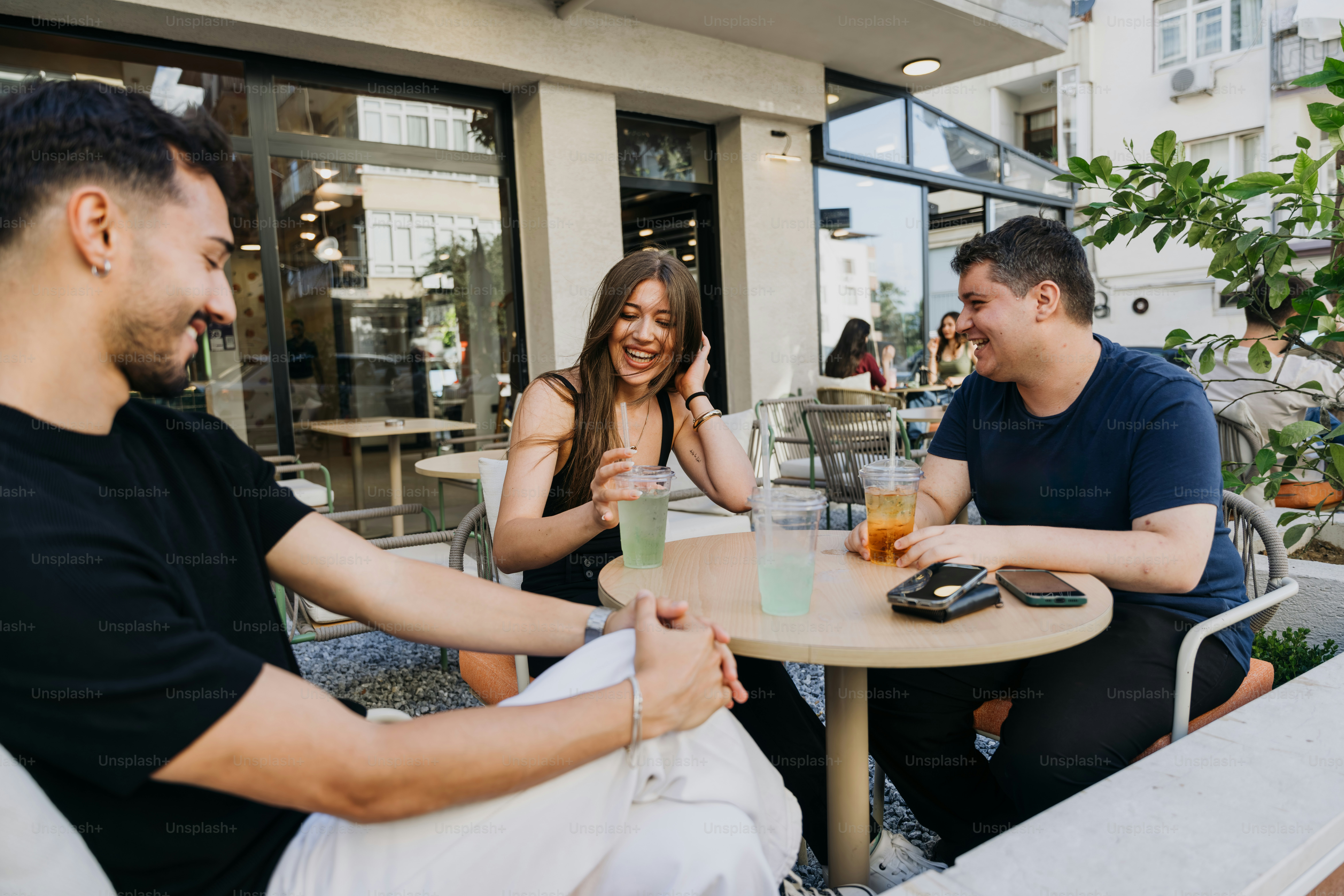Freunde, die bei Getränken in einem Café im Freien lachen