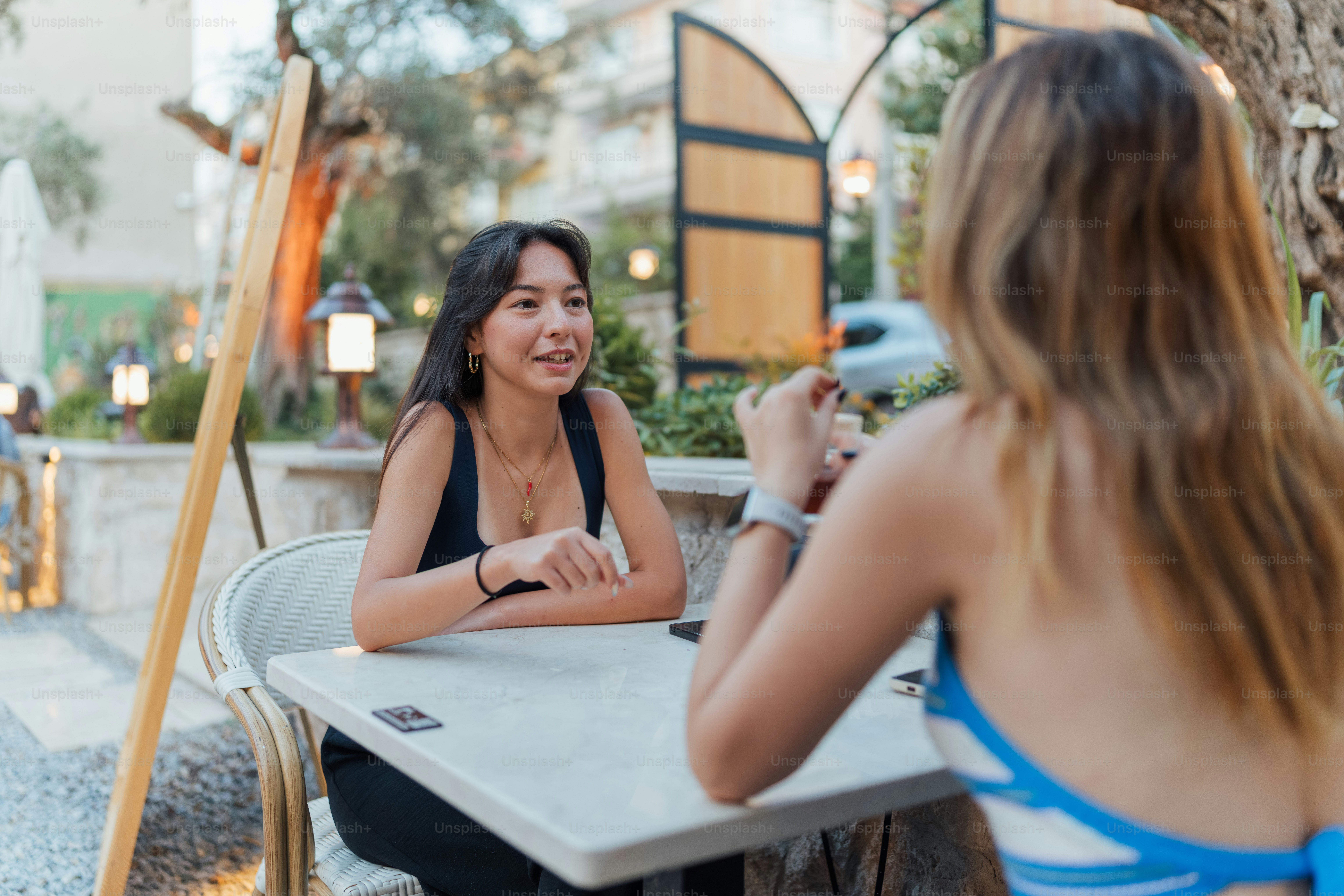 Zwei Frauen, die sich an einem Cafétisch im Freien unterhalten
