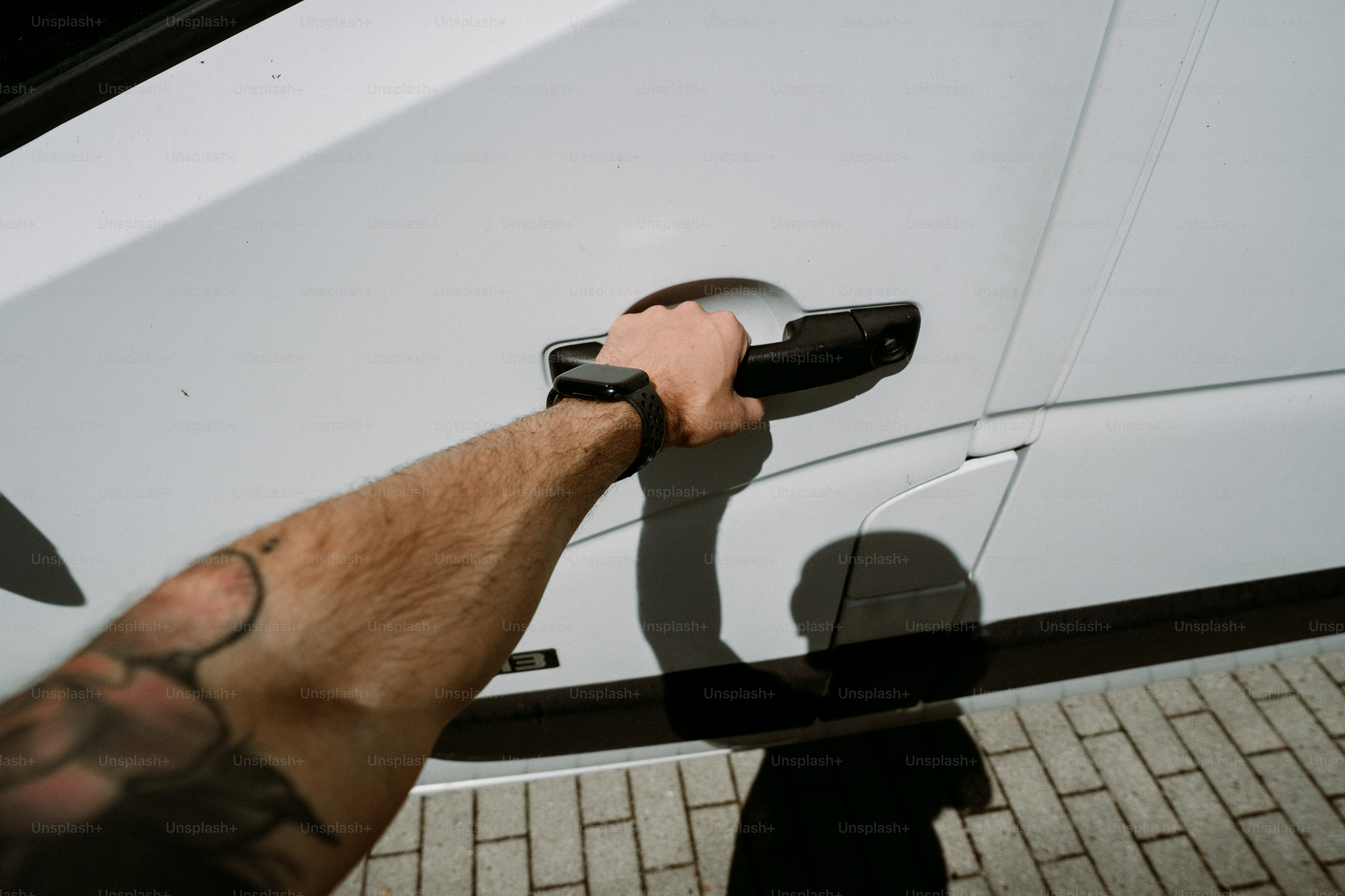 Tattooed hand opening white car door