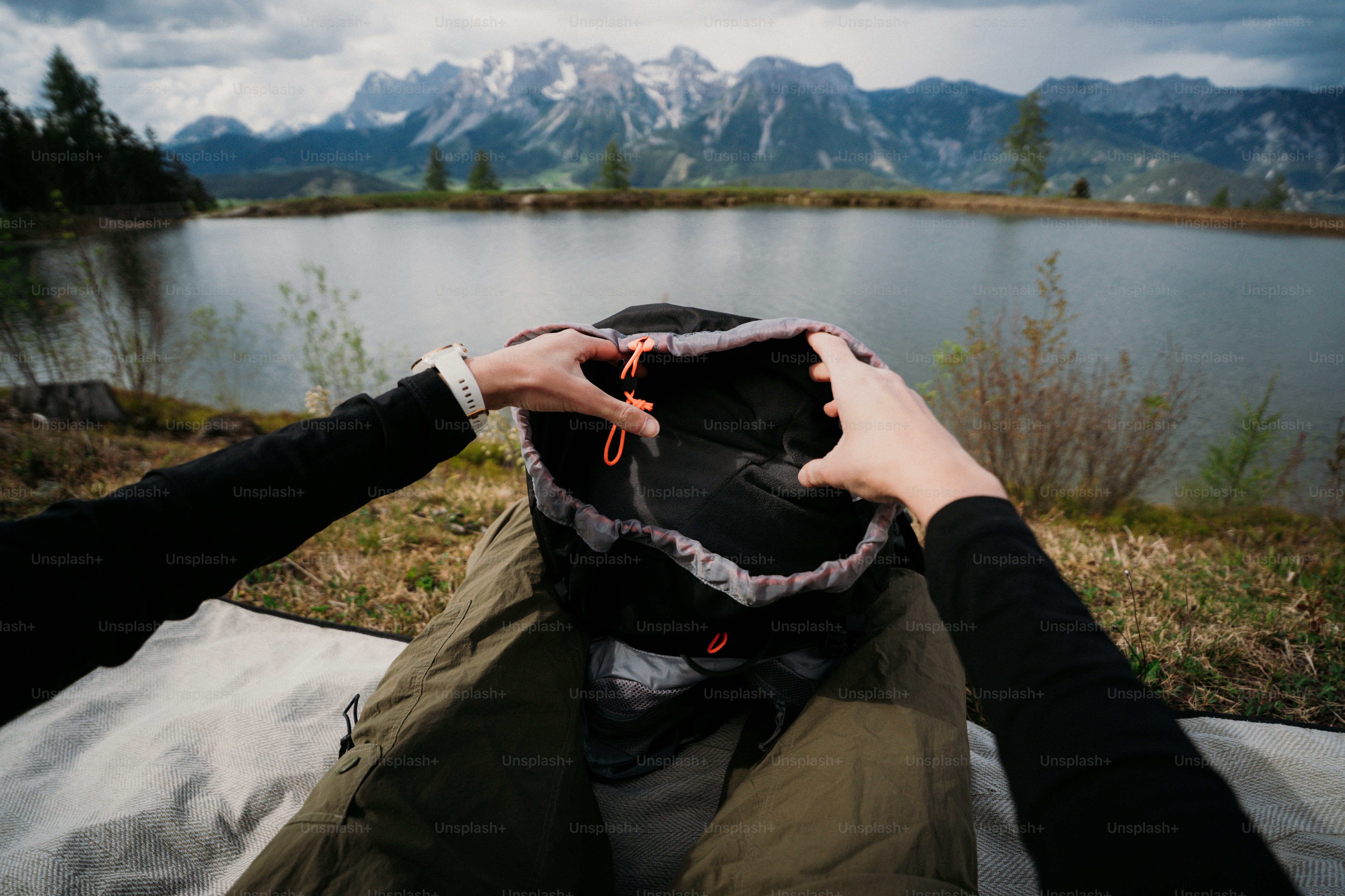 Opening backpack by a mountain lake