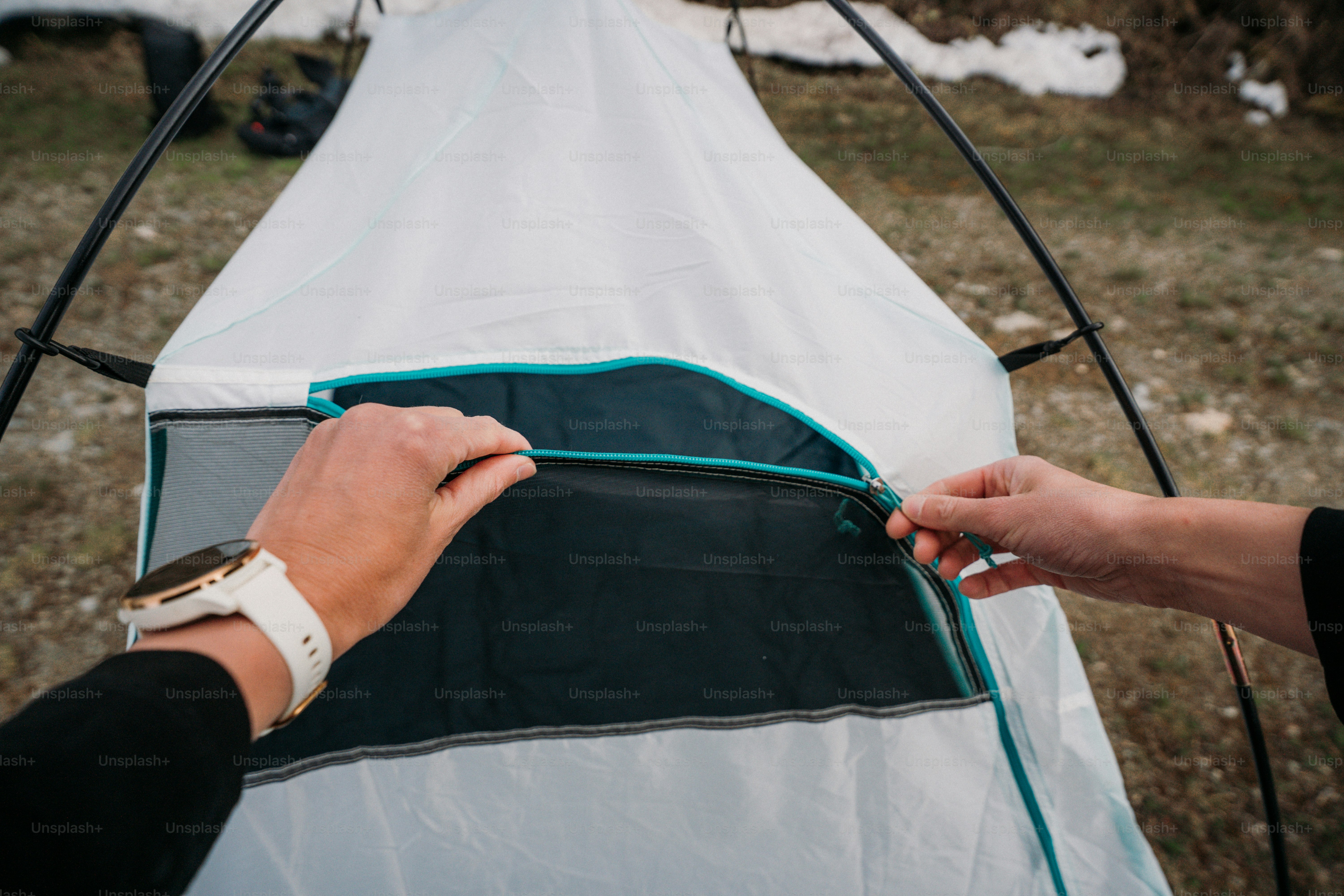 Zipping up a white and teal camping tent