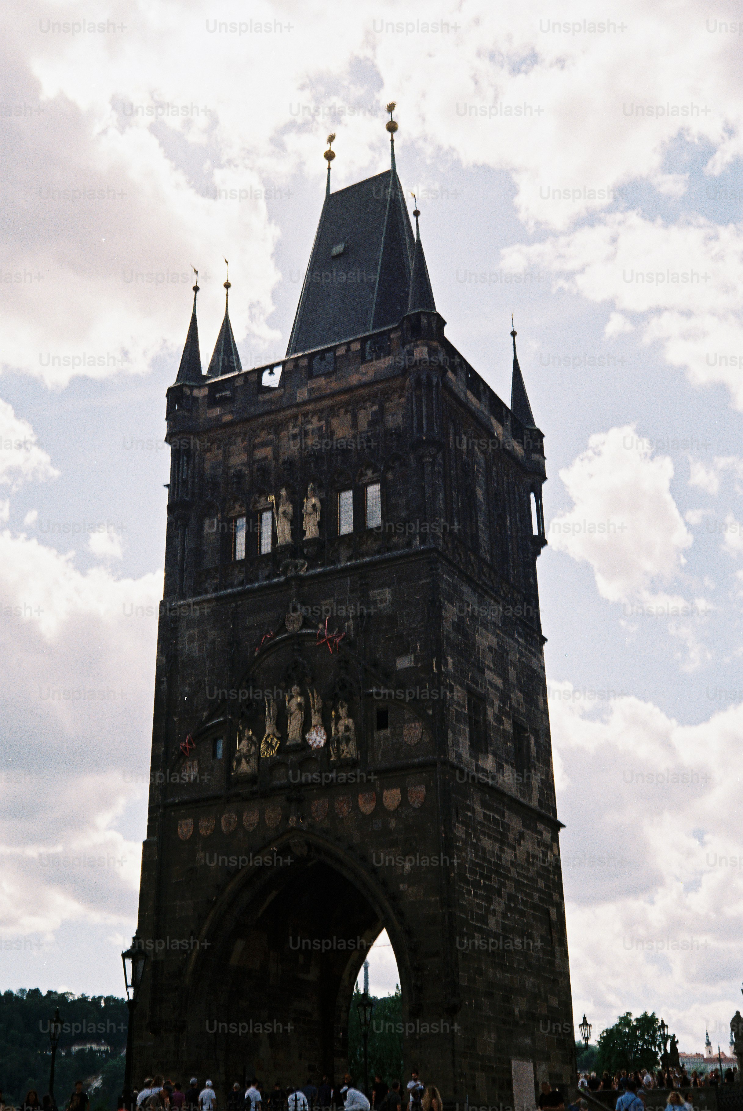 Dark stone tower with arched passageway and statues