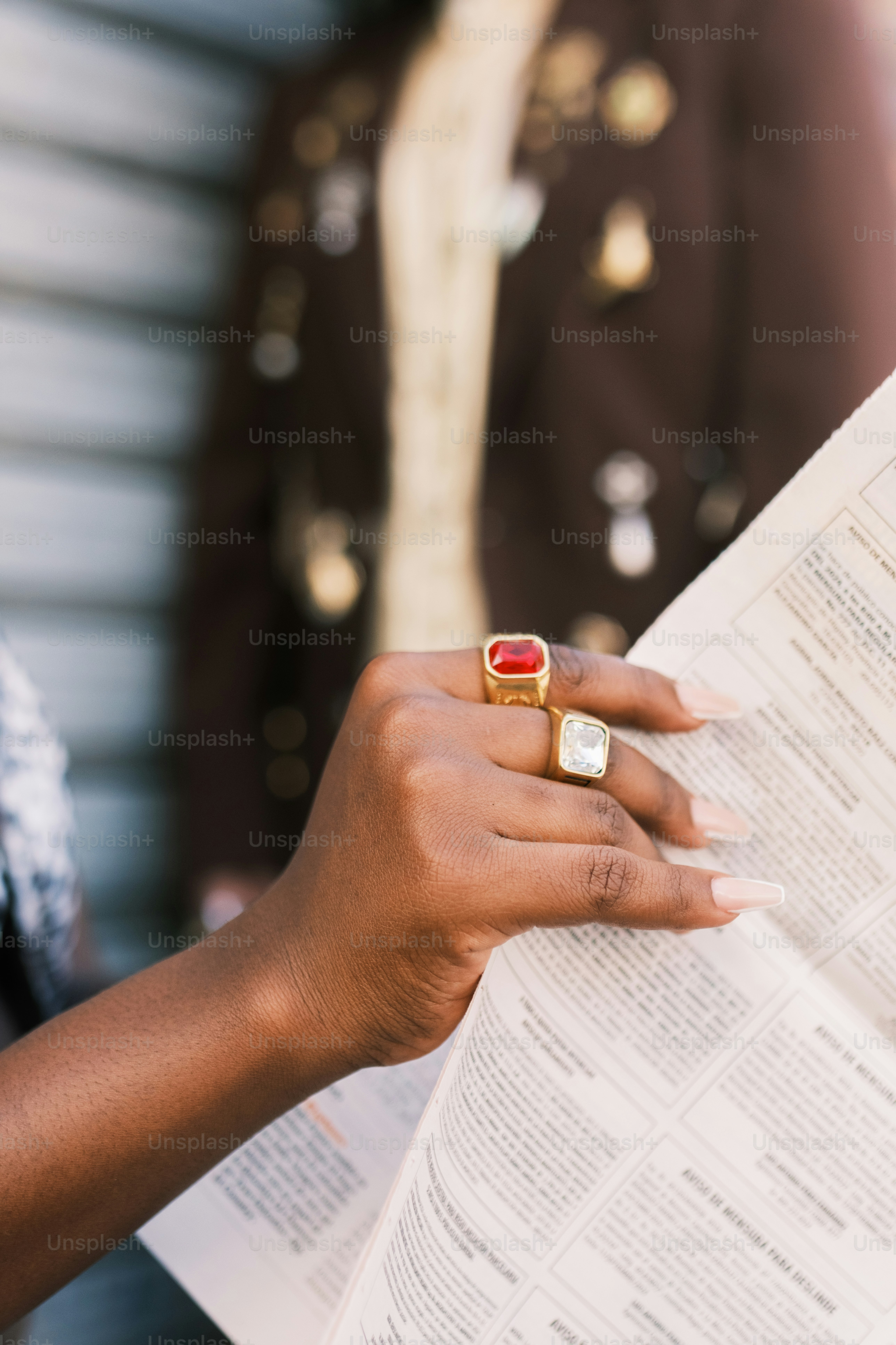 Mãos usando anéis segurando um jornal