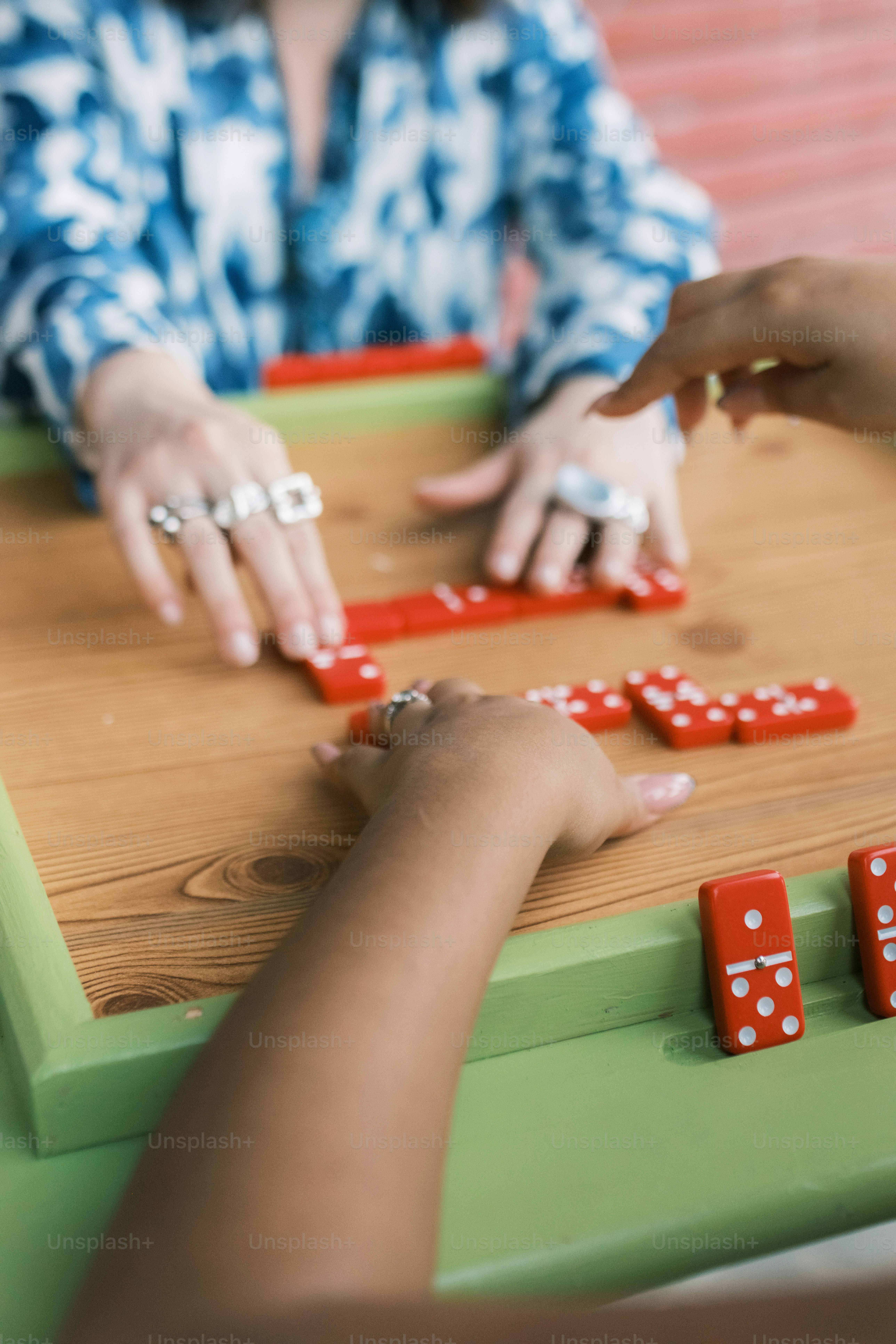 Pessoas jogando dominó em uma mesa de madeira com borda verde