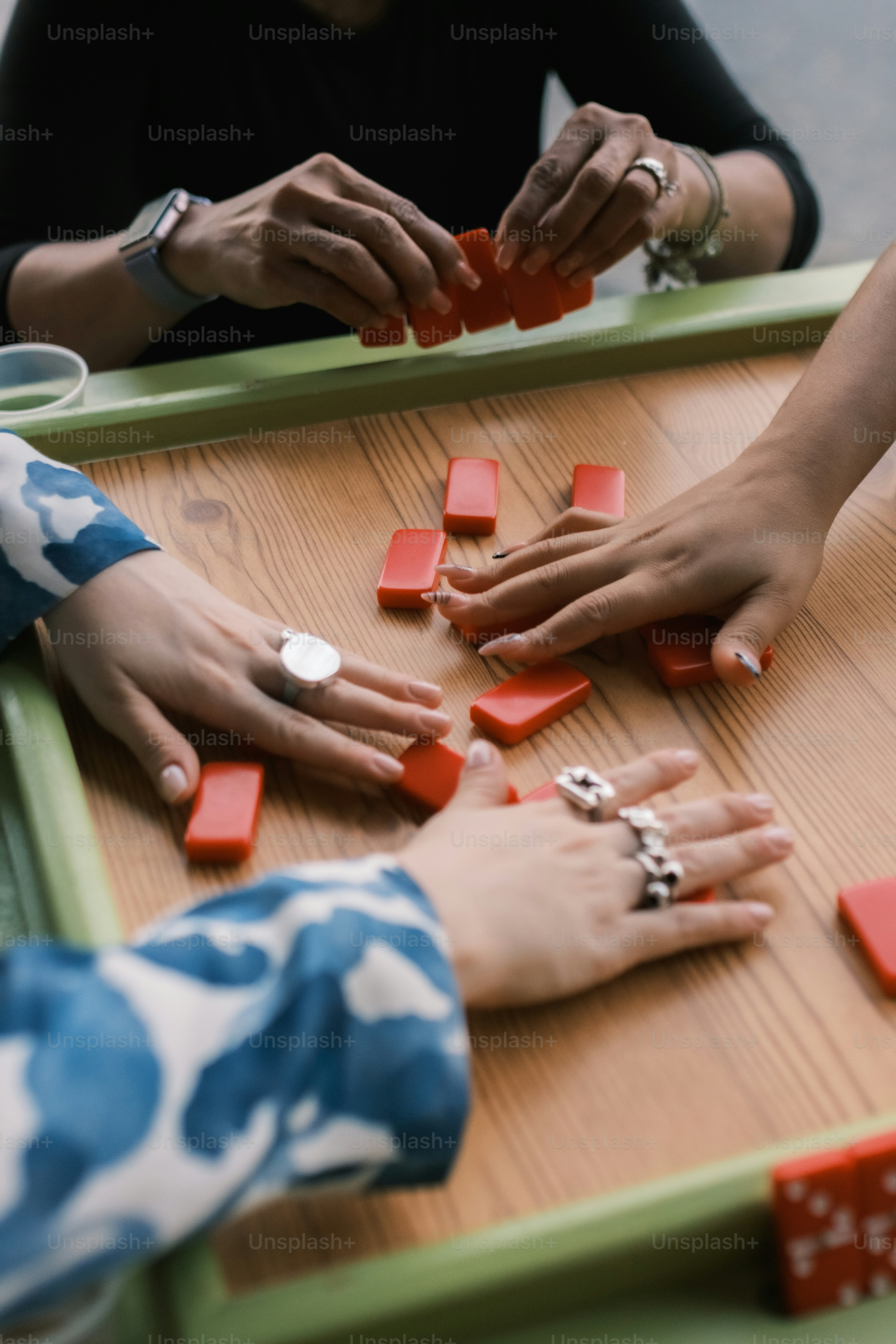 Três pessoas jogando dominó em uma mesa de madeira